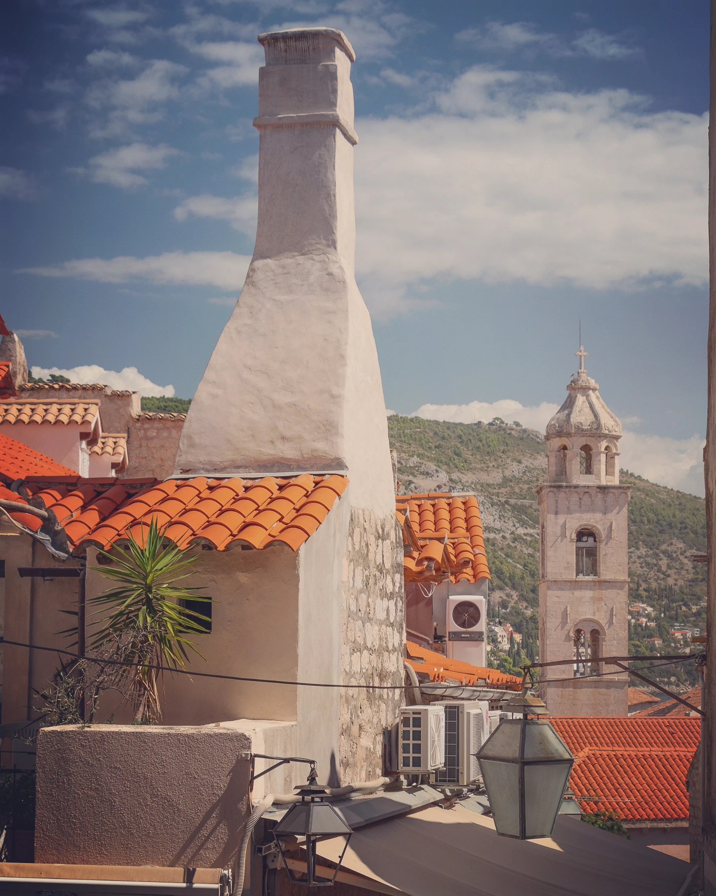 Rooftops and chimneys of Dubrovnik’s Old Town with the Dominican bell tower in the background.