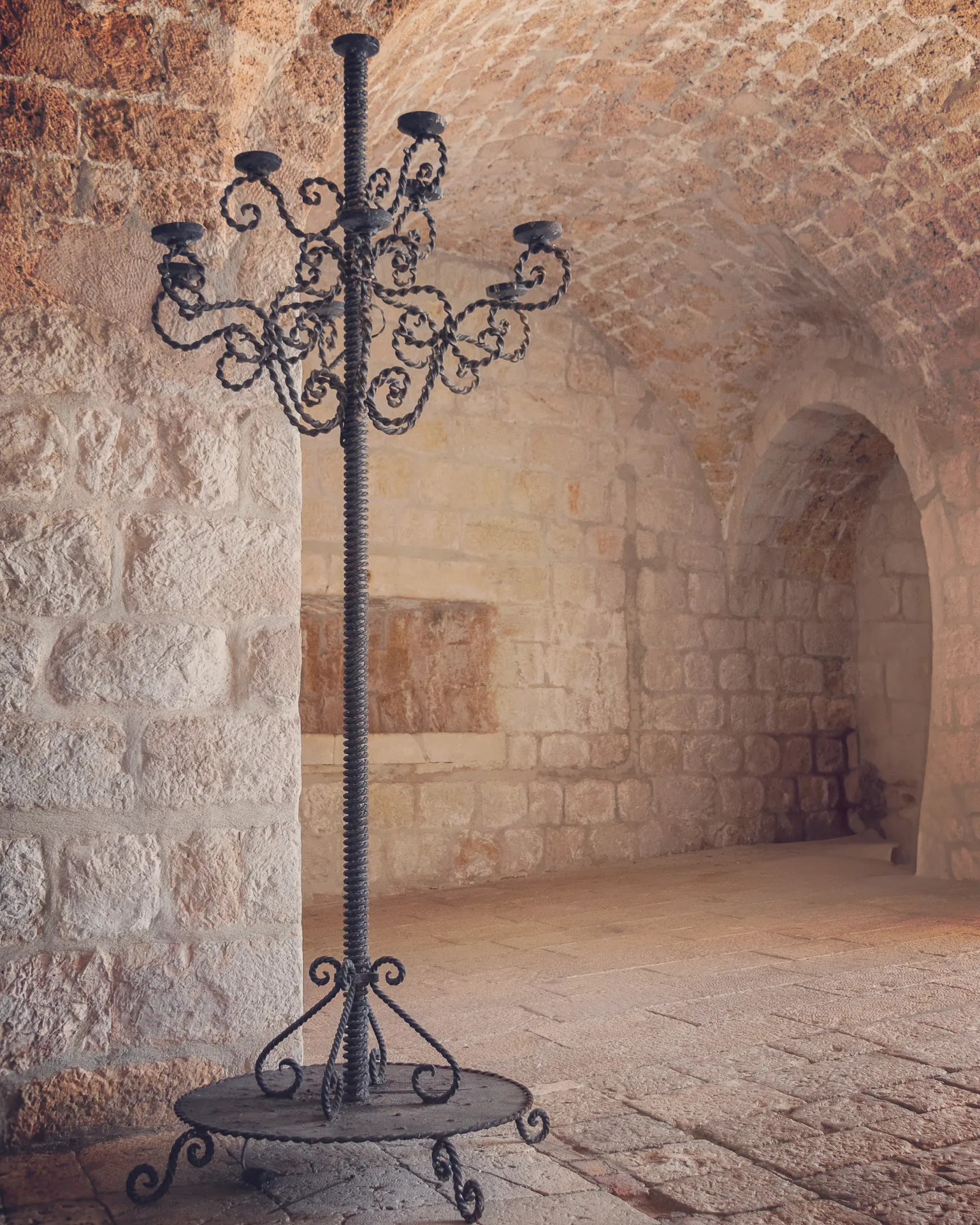 Wrought-iron candelabrum in a stone hall with arched ceilings in Dubrovnik, Croatia.