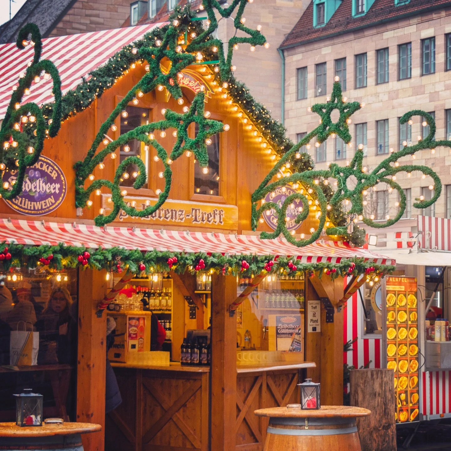 Wooden Glühwein stall at the Nuremberg Christmas Market decorated with green stars and festive lights.