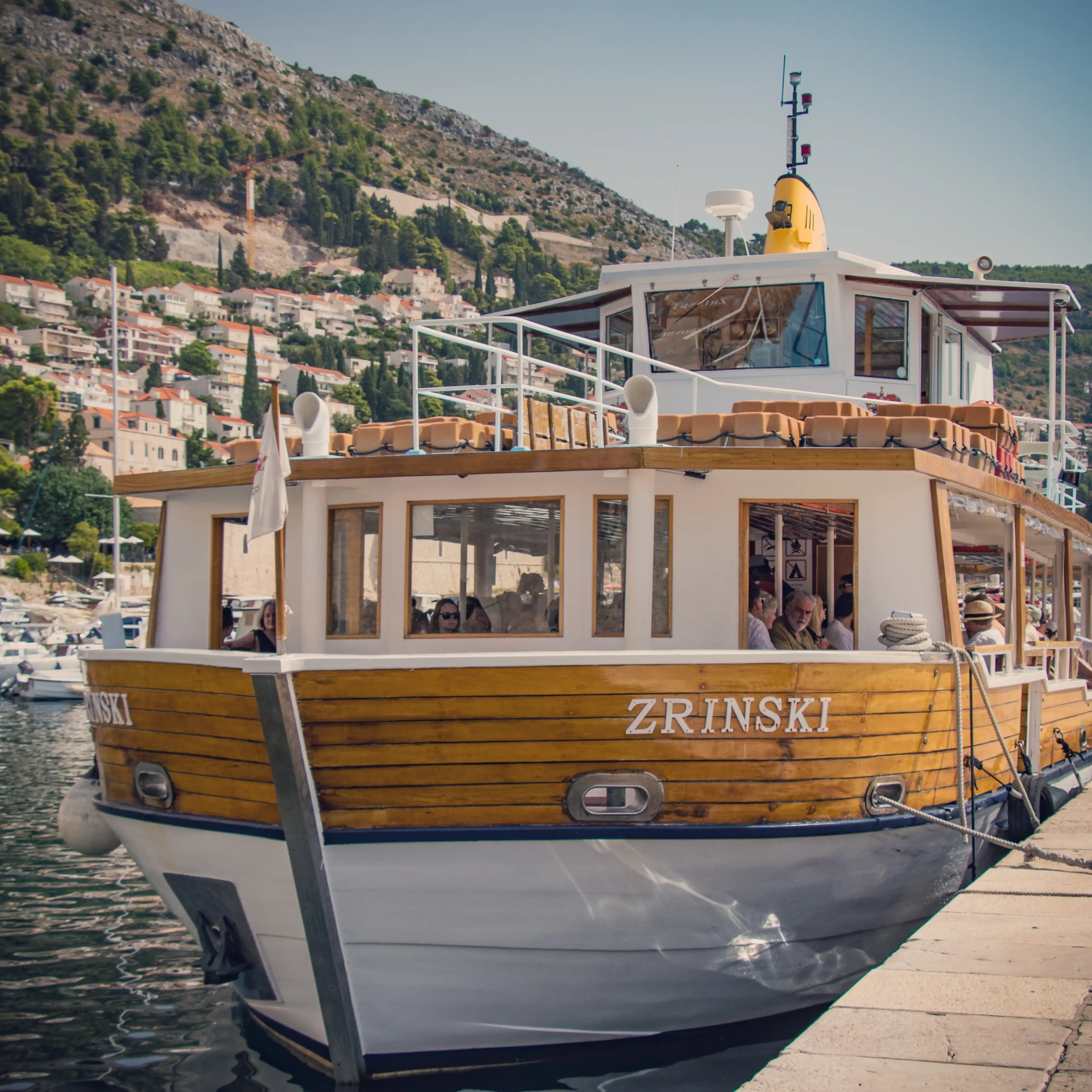 Wooden ferry named Zrinski docked in Dubrovnik’s harbor, preparing to depart for Lokrum Island.