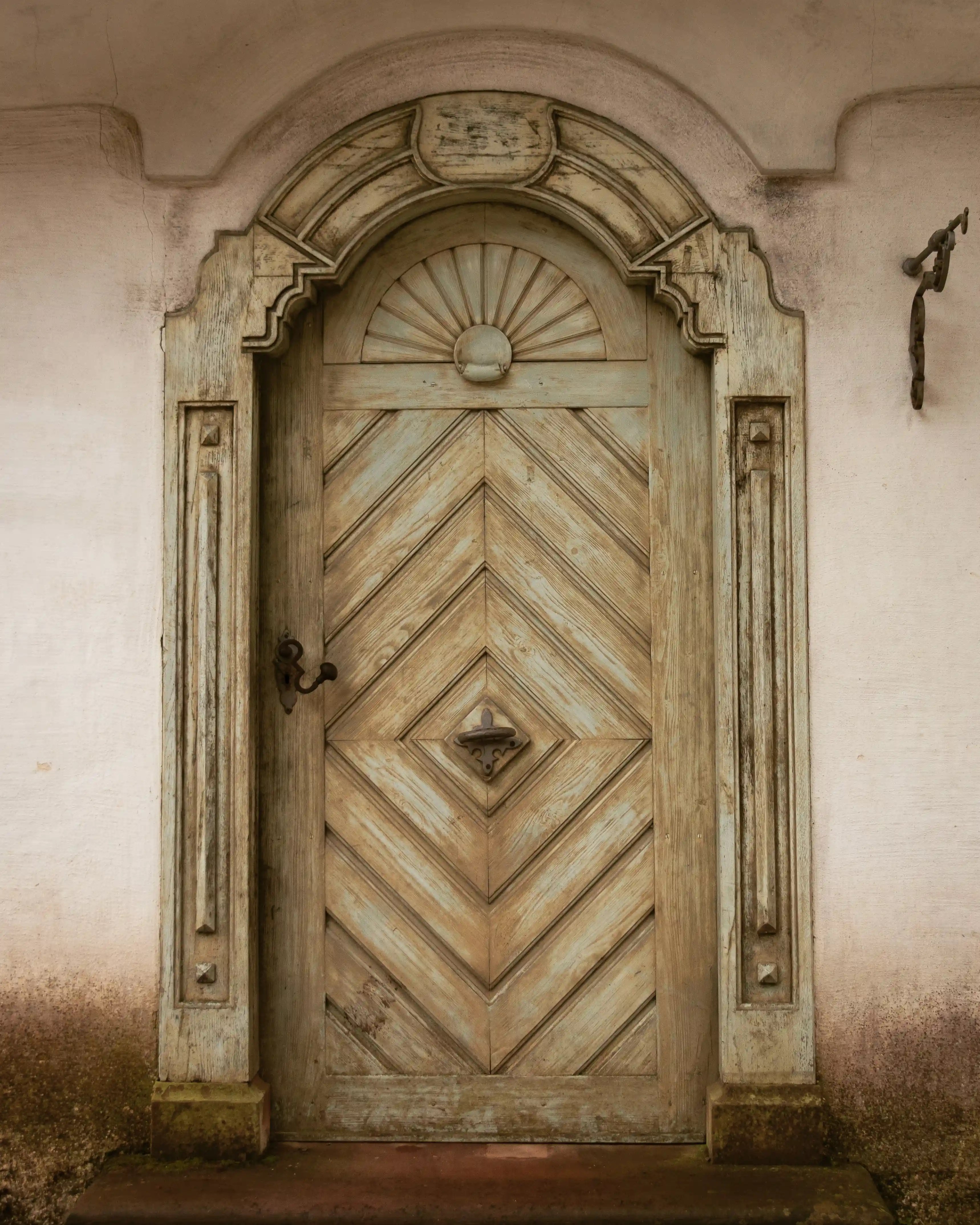 Ornate, weathered wooden door with chevron panels and carved details at Hofgut Sternen, Germany.