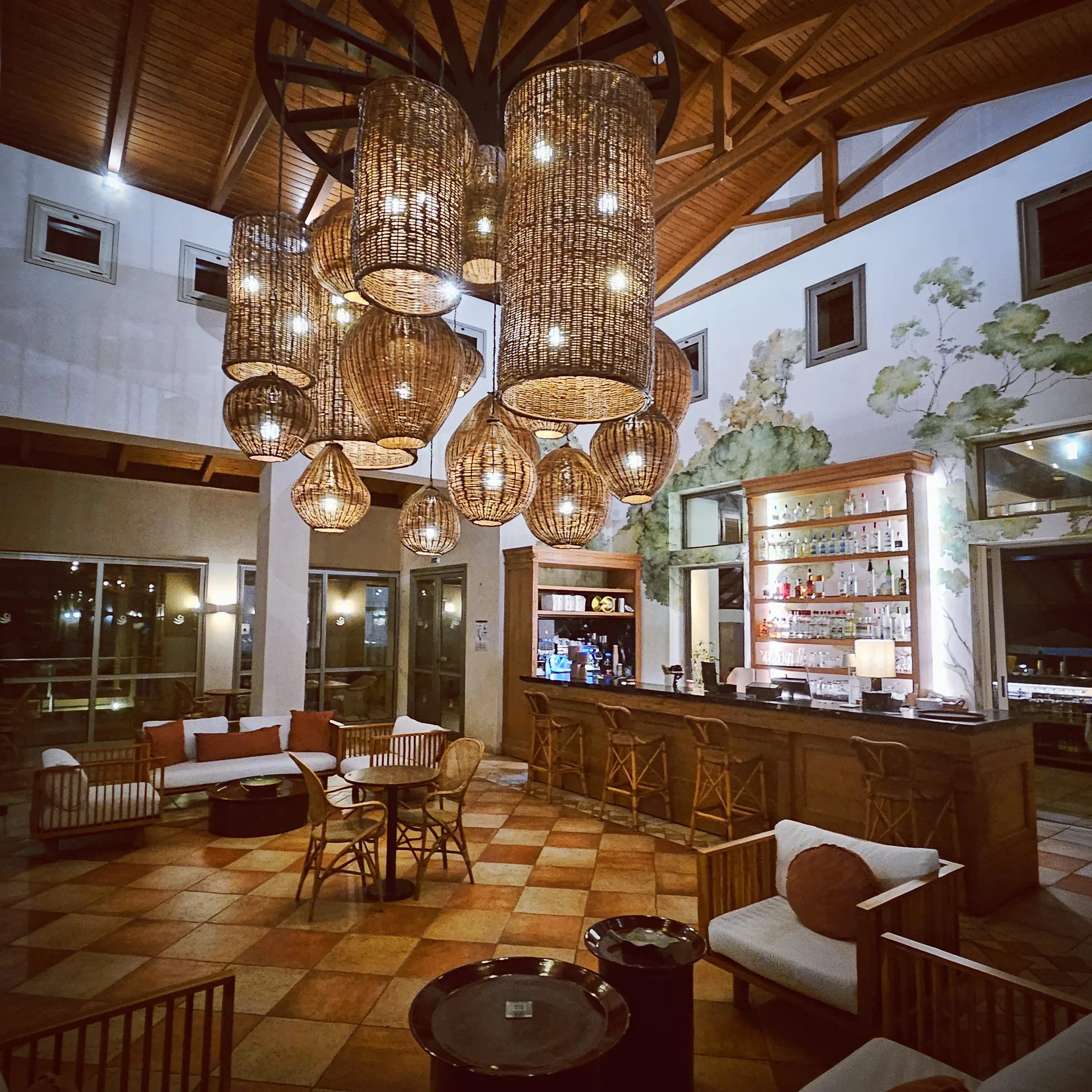 Warmly lit lobby bar with wicker pendant lights and cozy seating at Village Heights Resort in Hersonissos.