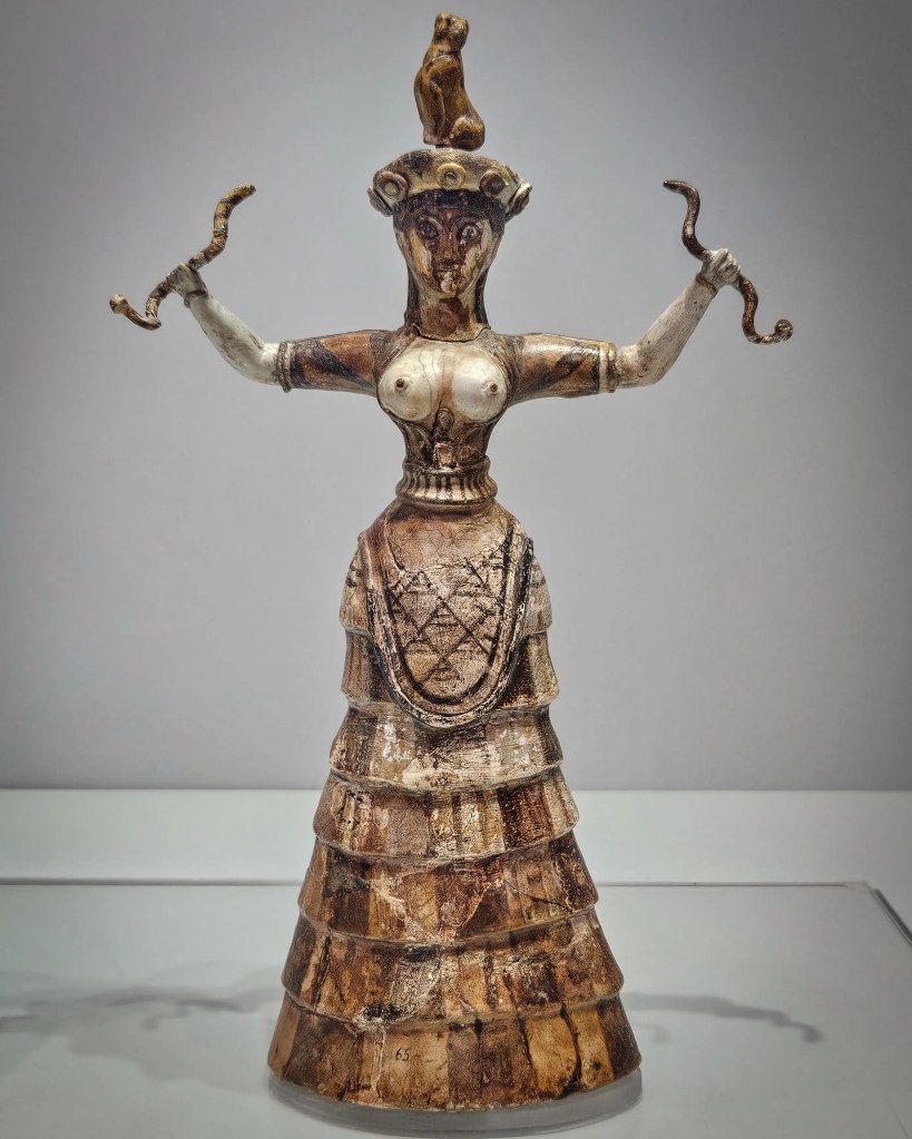 Minoan snake goddess figurine with raised arms and intricate skirt.