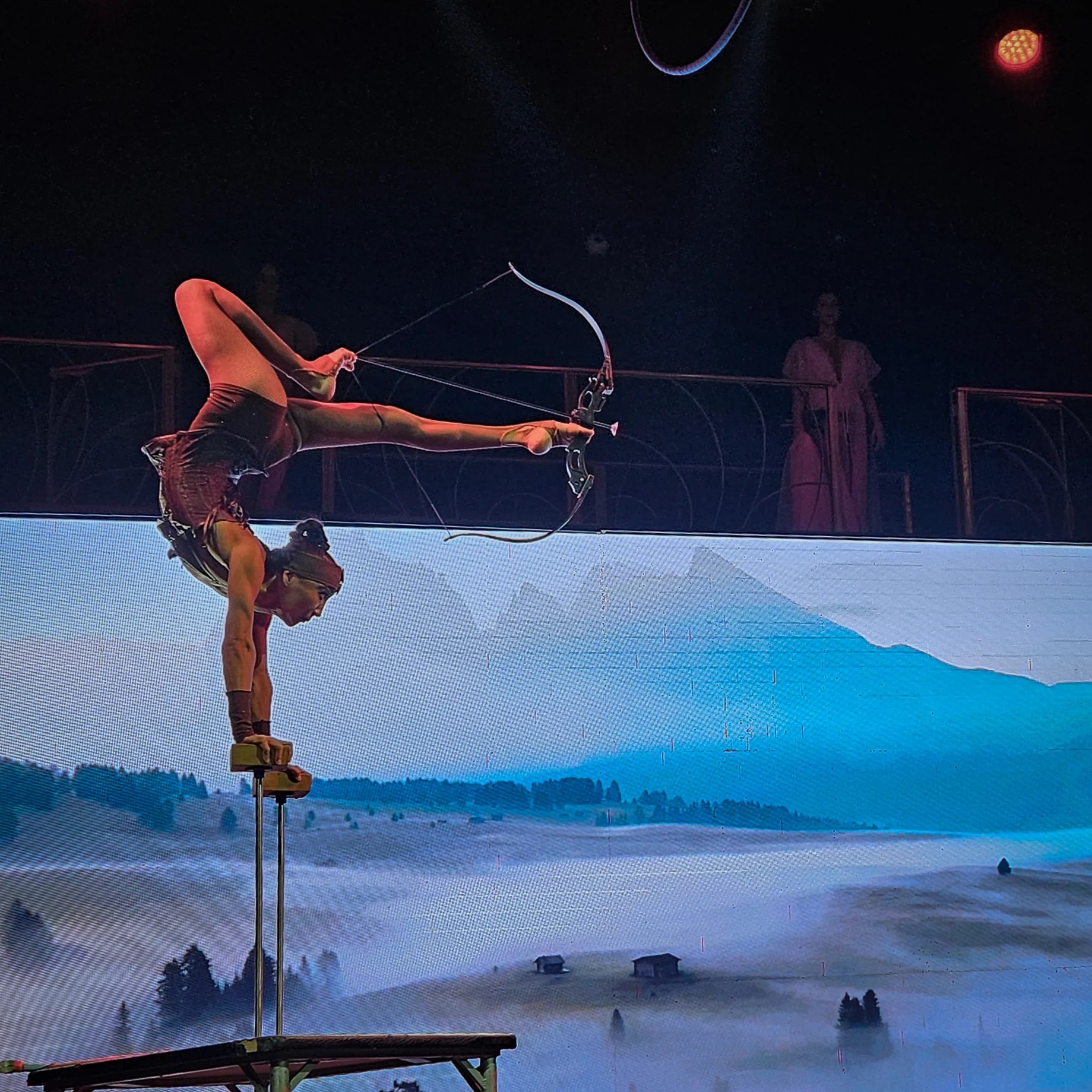 Contortionist performing an archery stunt upside down during the Troy Dinner Show in Crete.
