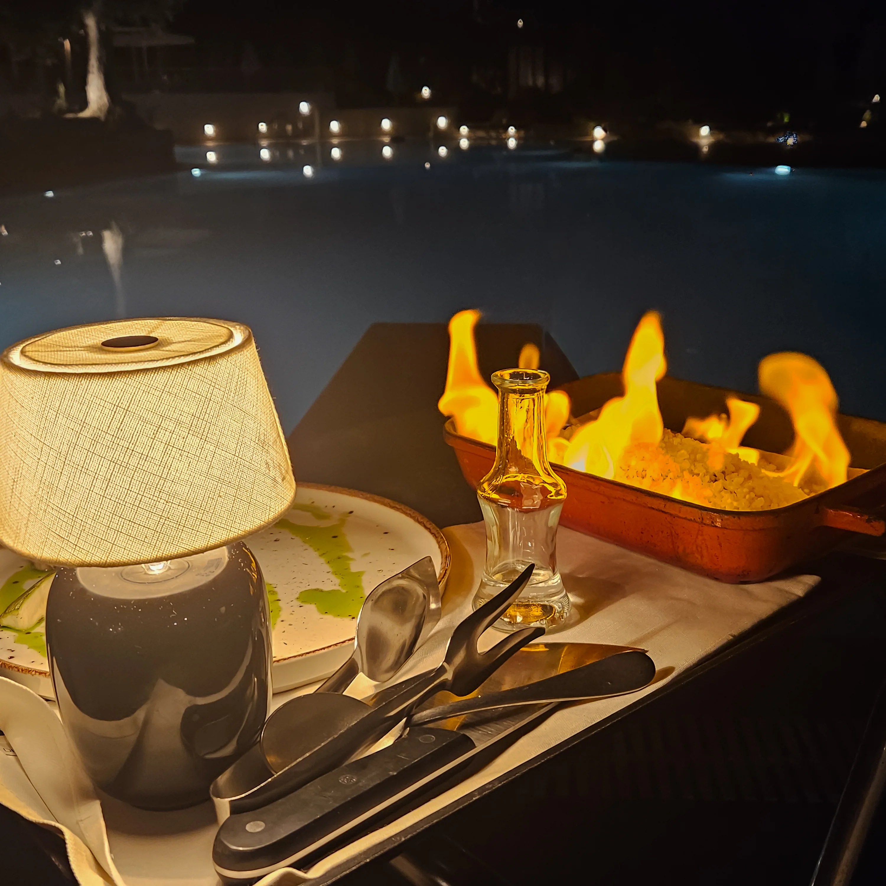 Flaming salted fish dish served beside the pool at Village Heights Resort restaurant at night.