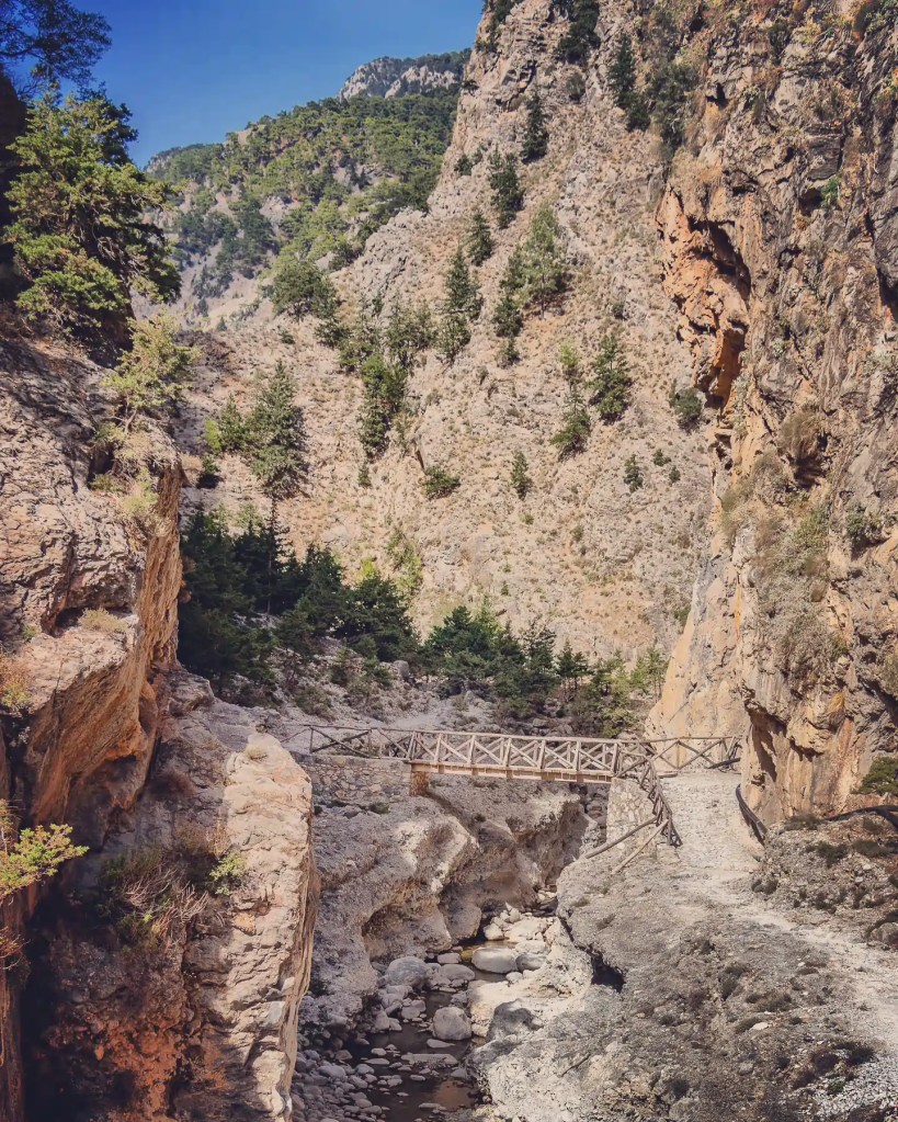 Wooden bridge crossing a rocky ravine between steep canyon walls.