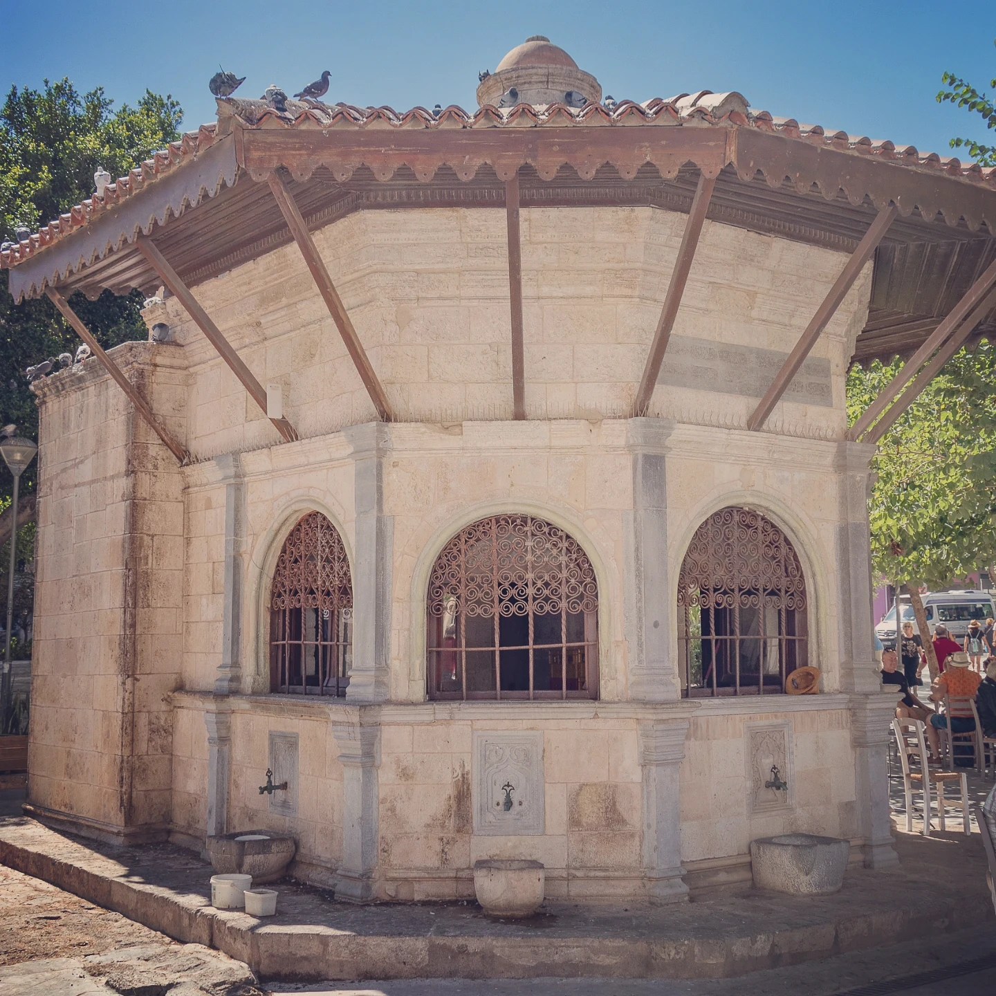 Ottoman-era stone fountain house in Heraklion with arched windows and decorative metal grilles.