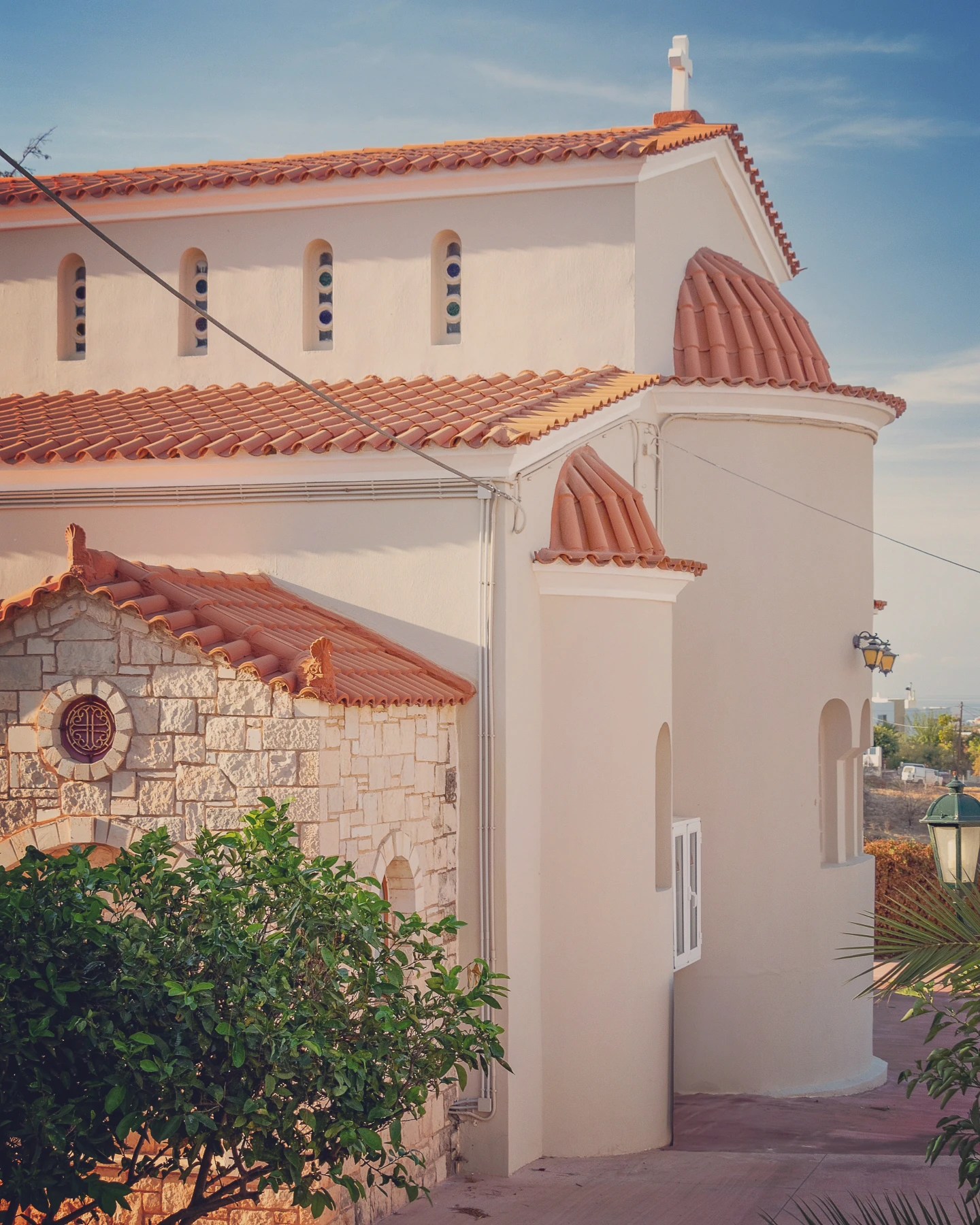 Cream-colored Orthodox church with terracotta roof tiles and arched windows in Ano Hersonissos, Crete.
