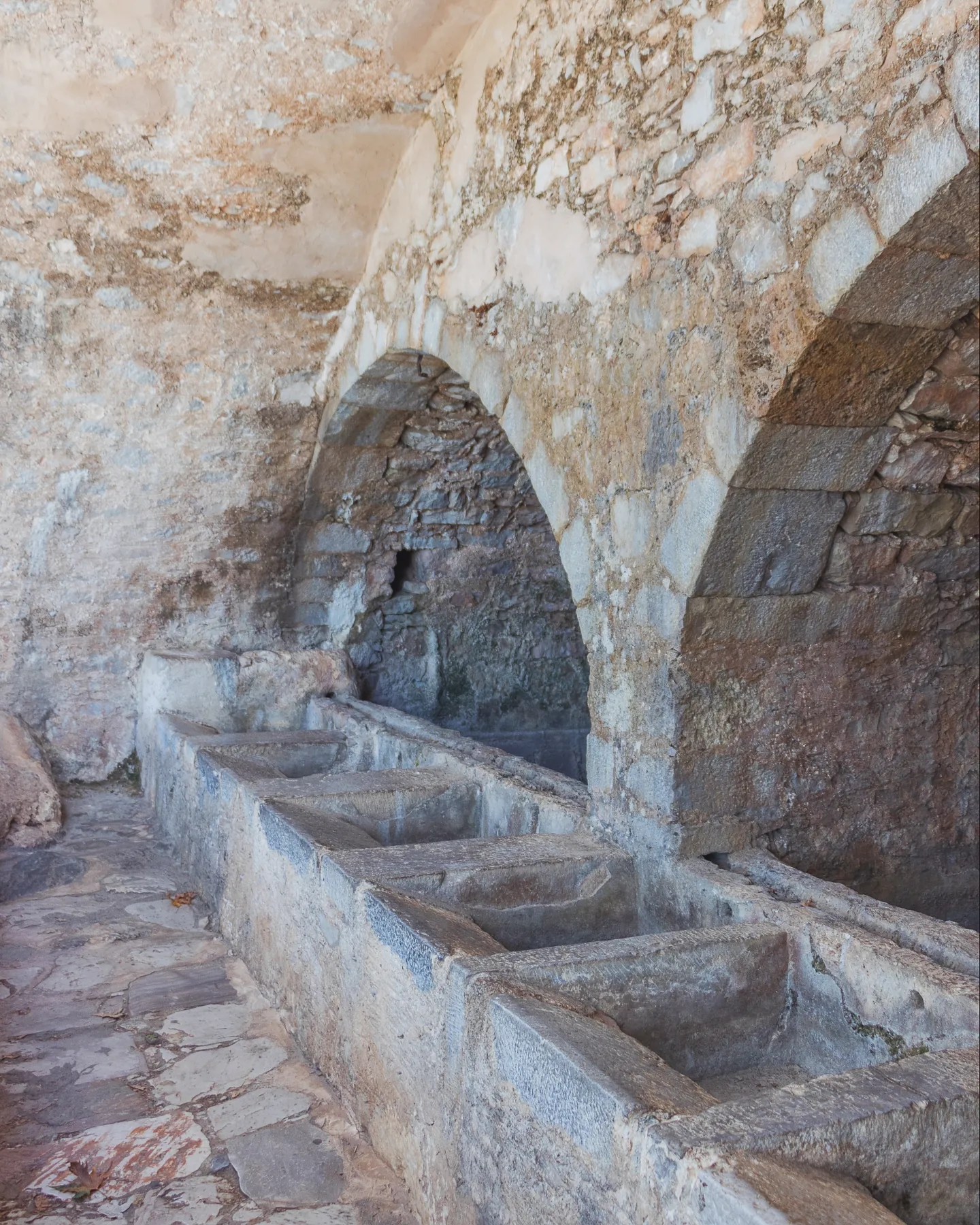 Row of stone basins and arched chambers inside the Megali Vrisi fountain structure in Krasi.
