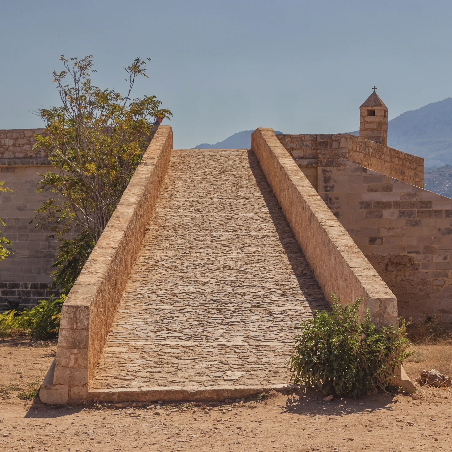 A long stone ramp inside the Rethymno Fortezza leading upward between low walls toward a small bell turret.