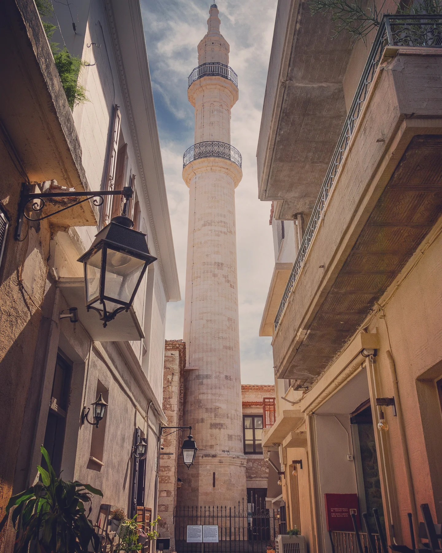 A tall stone minaret of the Nerantze Mosque rises between narrow buildings in Rethymno’s old town.