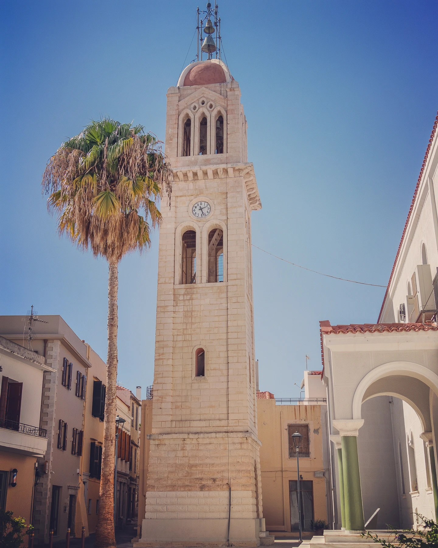 The tall bell tower of Megali Panagia rises beside a palm tree in Rethymno’s old town.