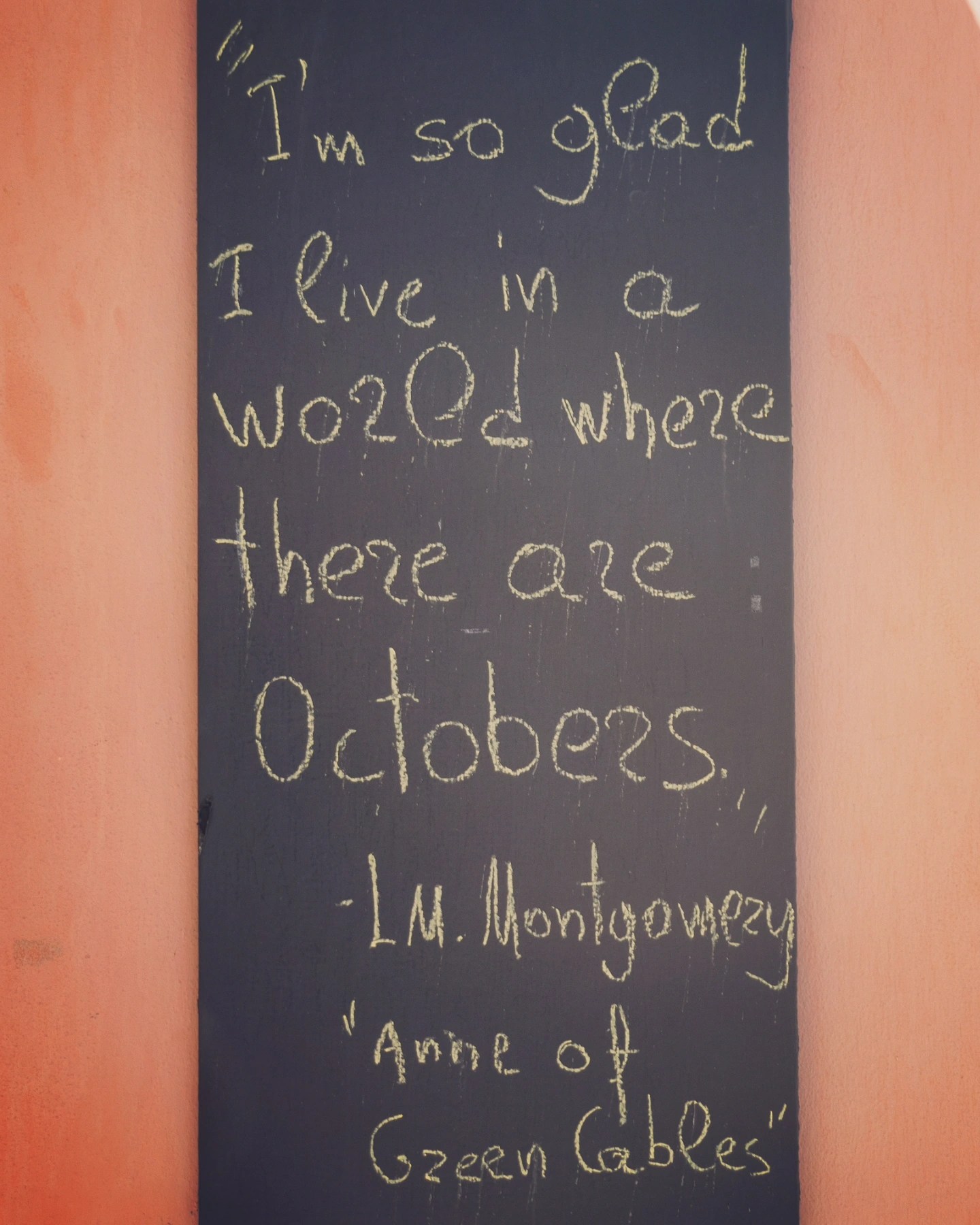 A chalkboard sign with a handwritten quote from “Anne of Green Gables” - “I’m so glad I live in a world where there are Octobers,”