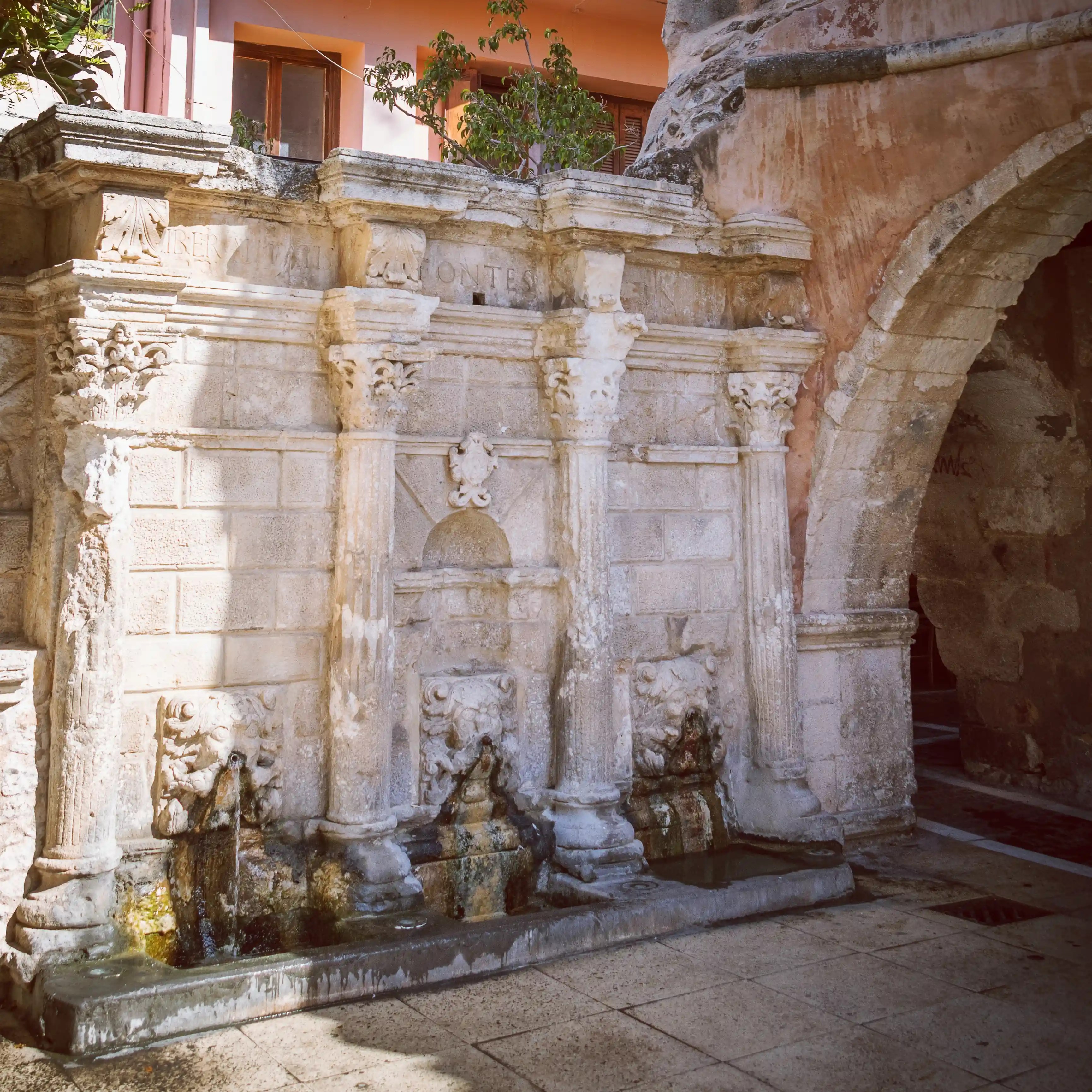 The Rimondi Fountain in Rethymno with its stone columns, carved lion heads, and flowing water.