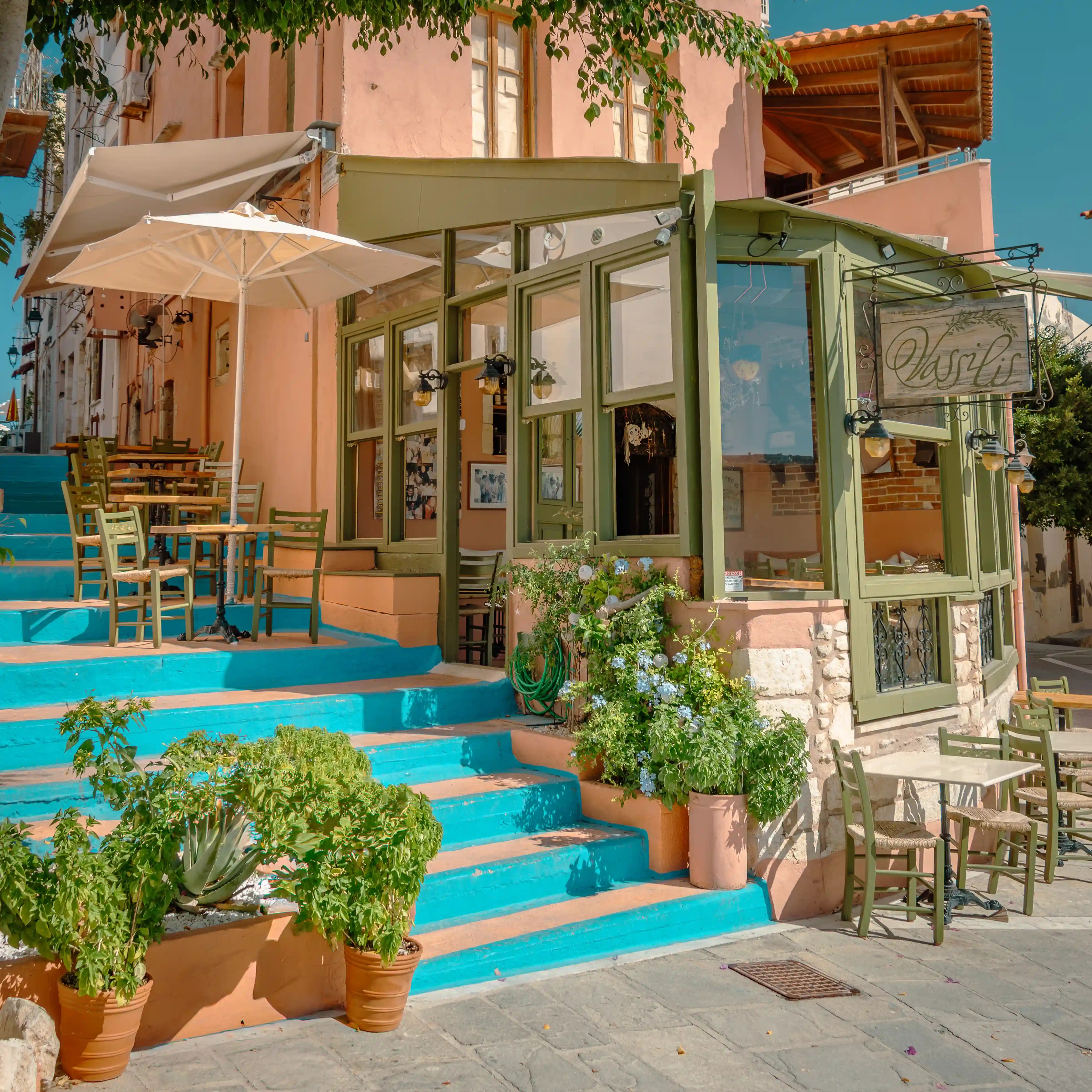 Colorful café with turquoise steps, peach walls, and potted plants.