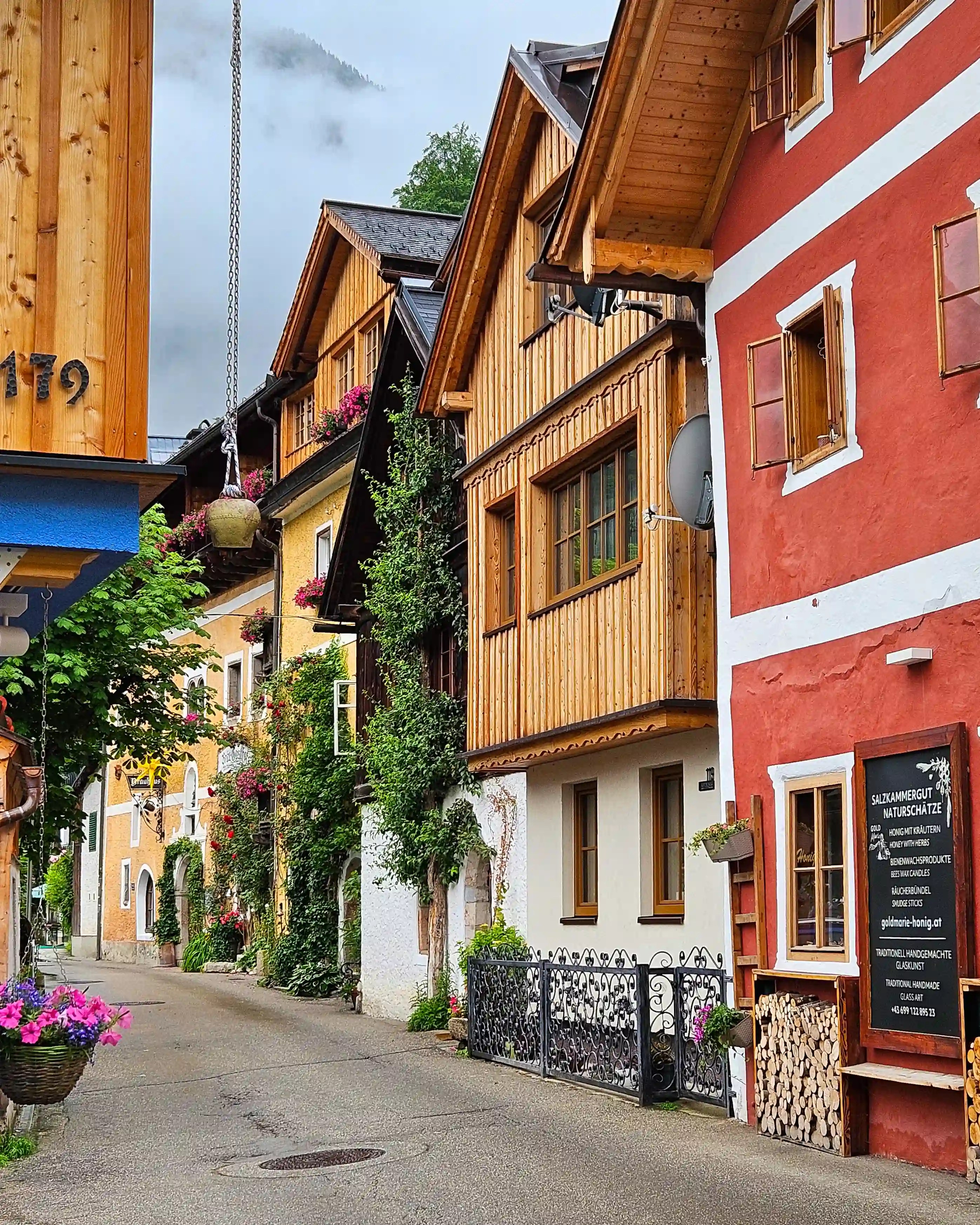 A narrow street in Hallstatt lined with wooden houses, flower boxes, and colorful façades.