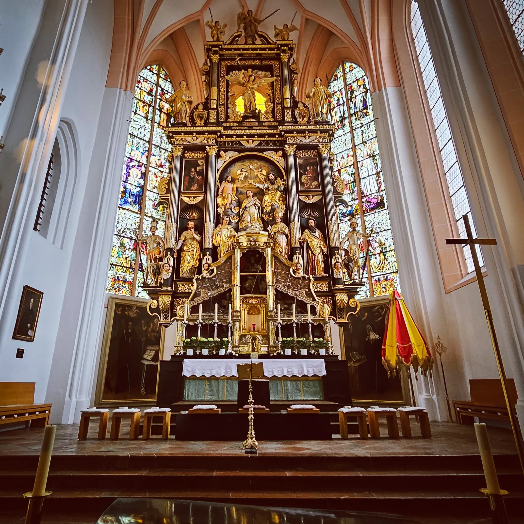 The richly decorated high altar inside Basilika Mondsee rises beneath a vaulted ceiling, framed by stained glass windows and gilded Baroque sculptures.
