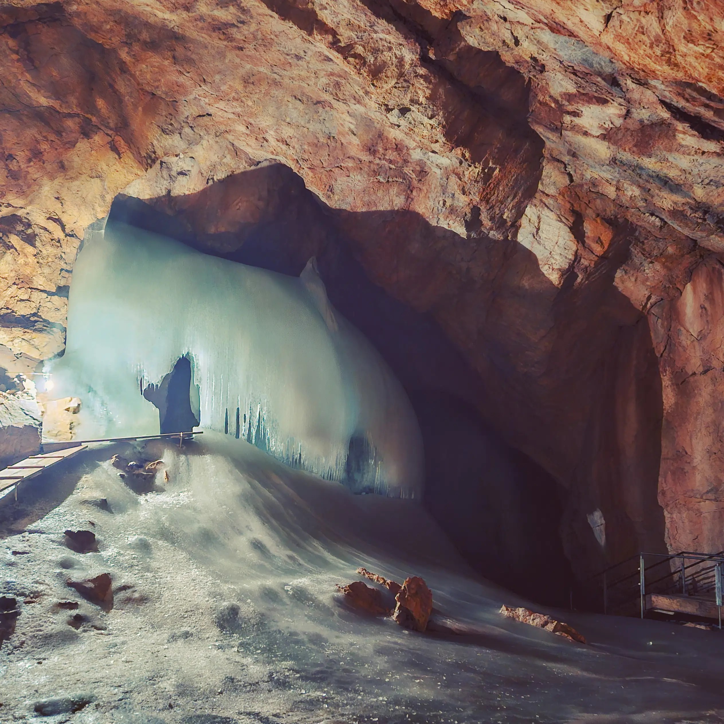 A massive ice formation inside Eisriesenwelt, glowing pale blue beneath an arched rock ceiling.