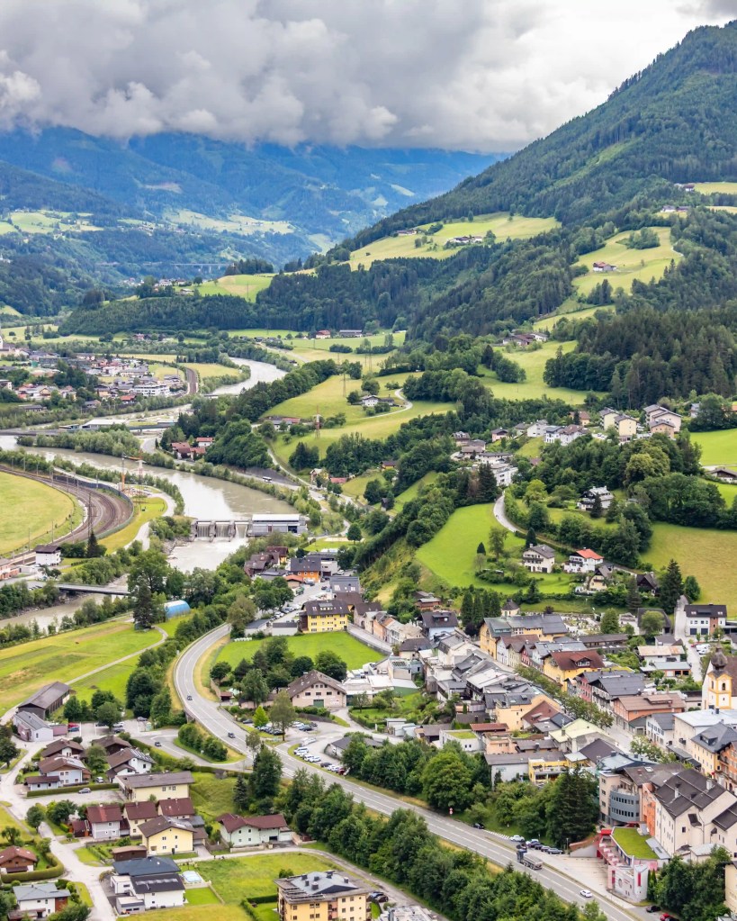 A panoramic view shows the town of Werfen, winding roads, and the Salzach River far below Burg Hohenwerfen.