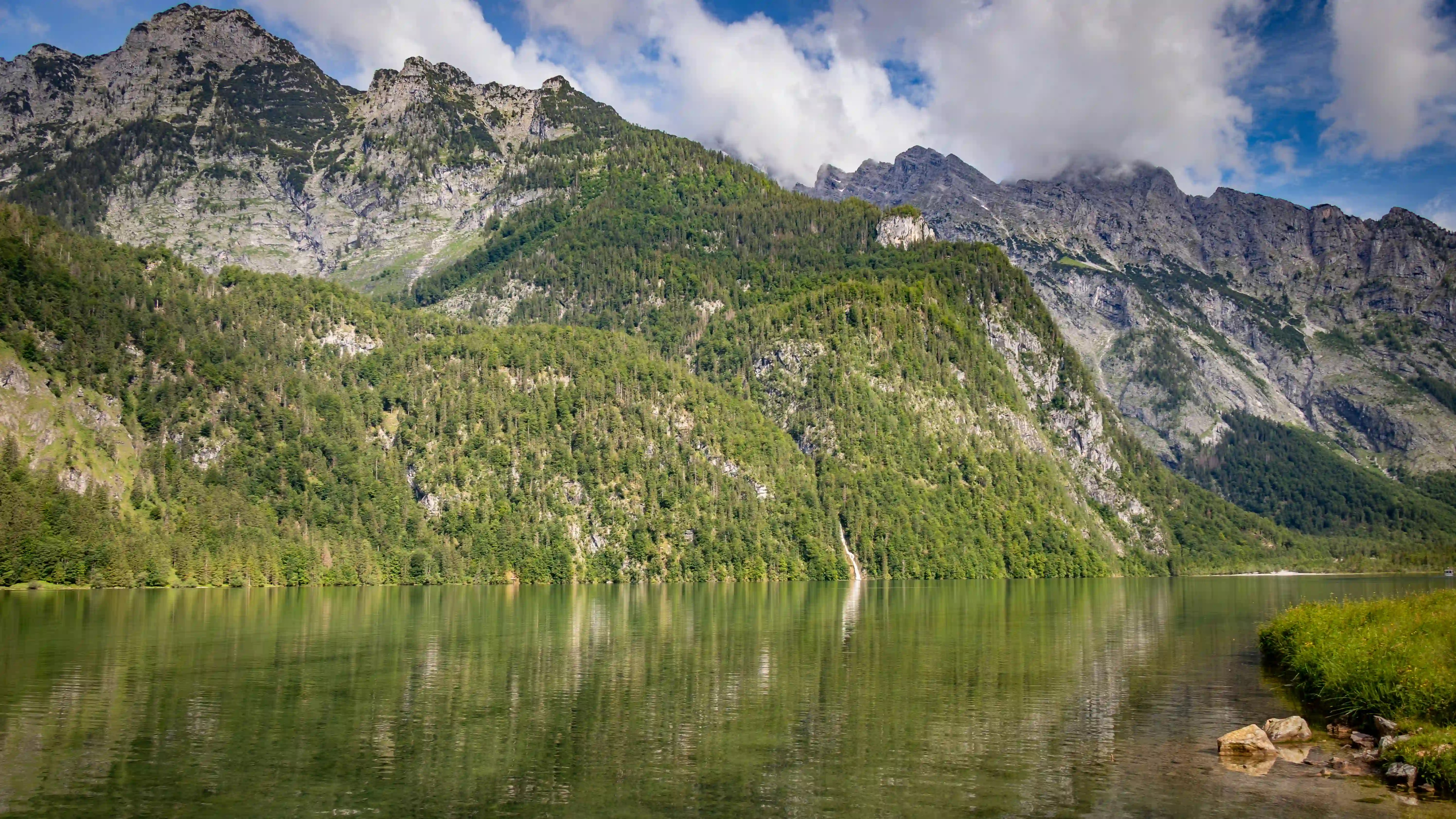 Mountains and trees reflect softly in the still green water of Königssee near the Salet landing.