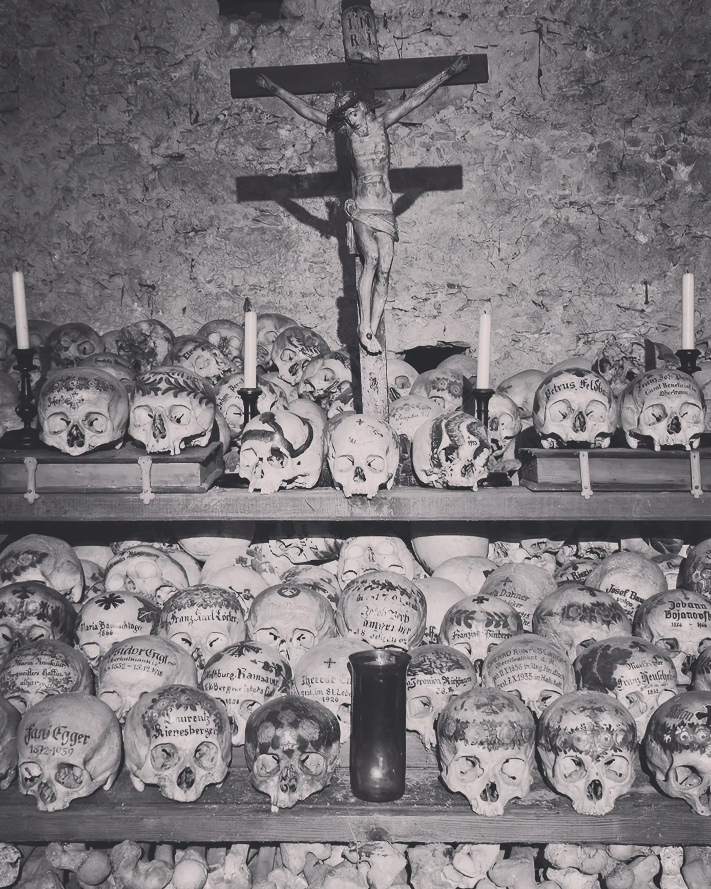 Painted human skulls arranged on shelves beneath a crucifix inside the Hallstatt Bone House.