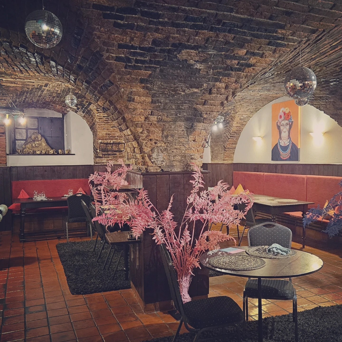 A dining room with low brick vault ceilings, wooden tables, upholstered benches, and soft lighting inside St. Peter’s Stiftskulinarium.