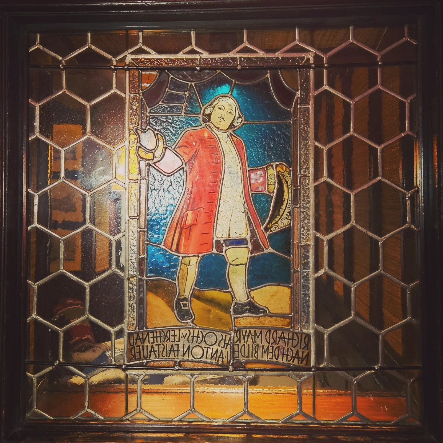 A stained glass window depicting a historical figure, set within leaded glass panels at St. Peter’s Stiftskulinarium.