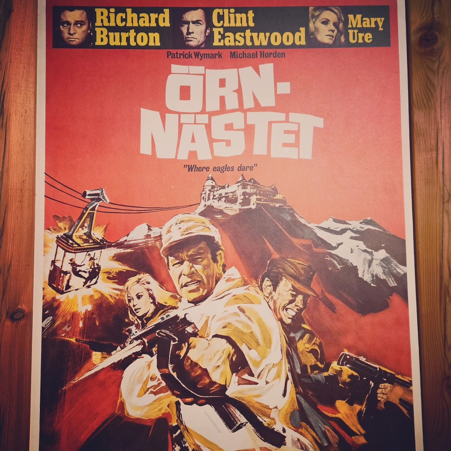 A vintage movie poster for “Where Eagles Dare” hangs on a wooden wall inside Burg Hohenwerfen.