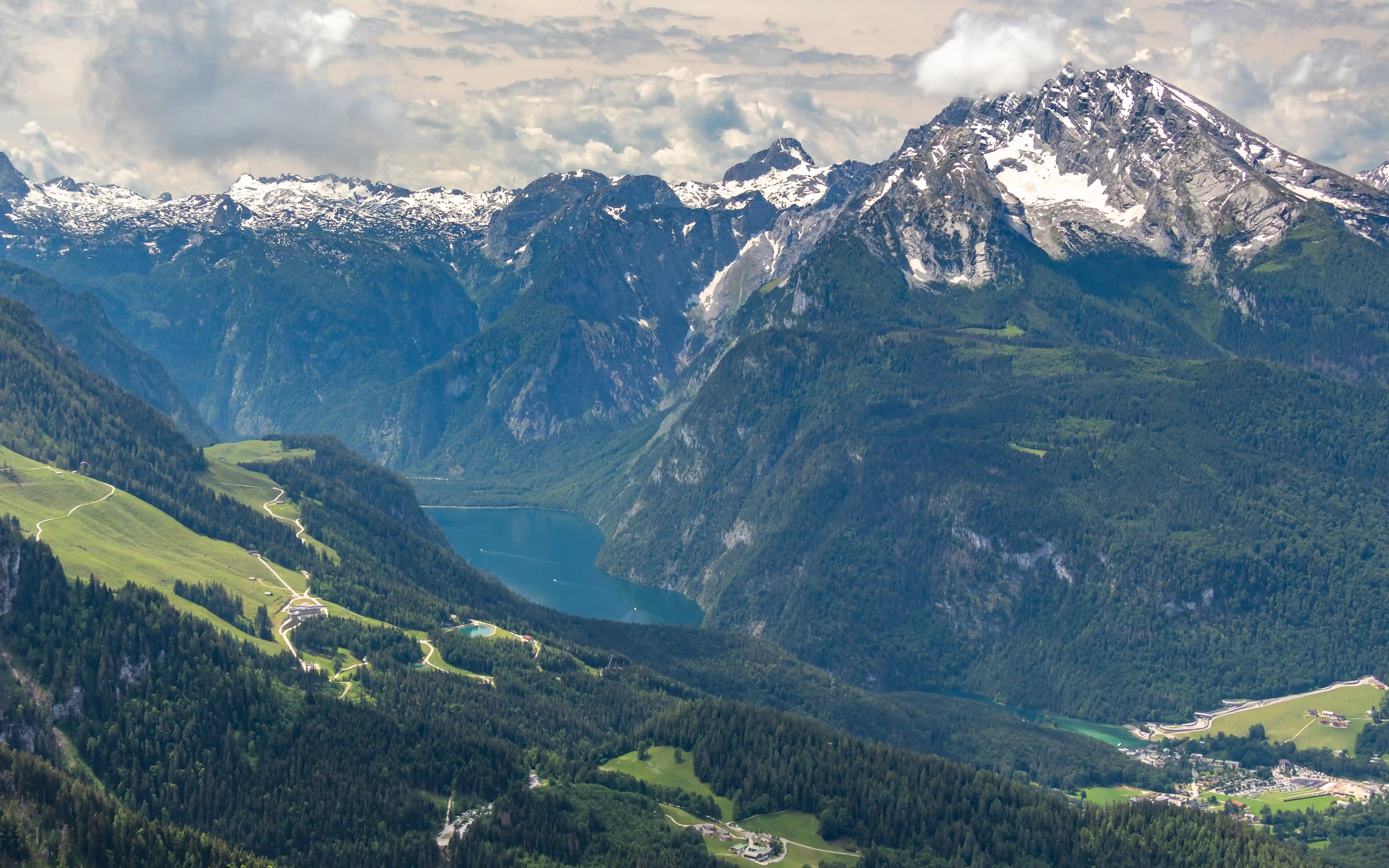 A closer view of a narrow alpine lake surrounded by steep cliffs and snow-dusted mountain peaks.