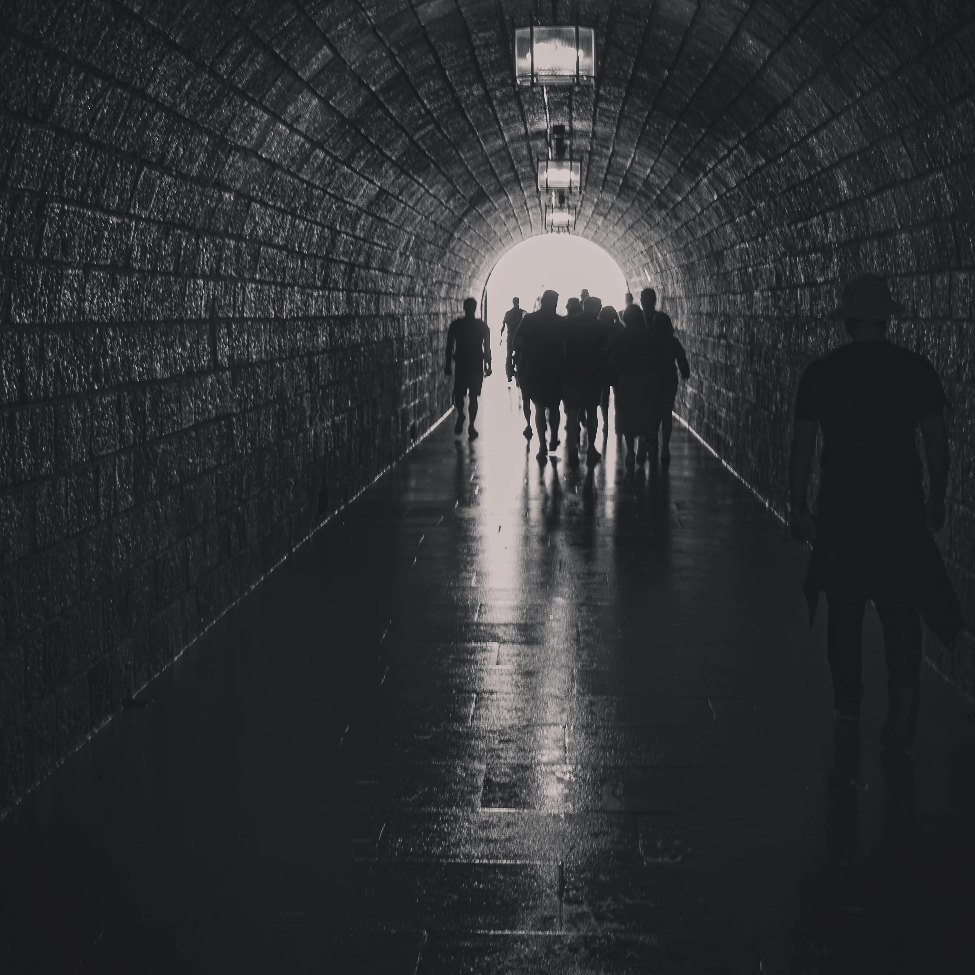 Silhouetted visitors walking through a long, arched tunnel toward a bright opening at the Eagle’s Nest.