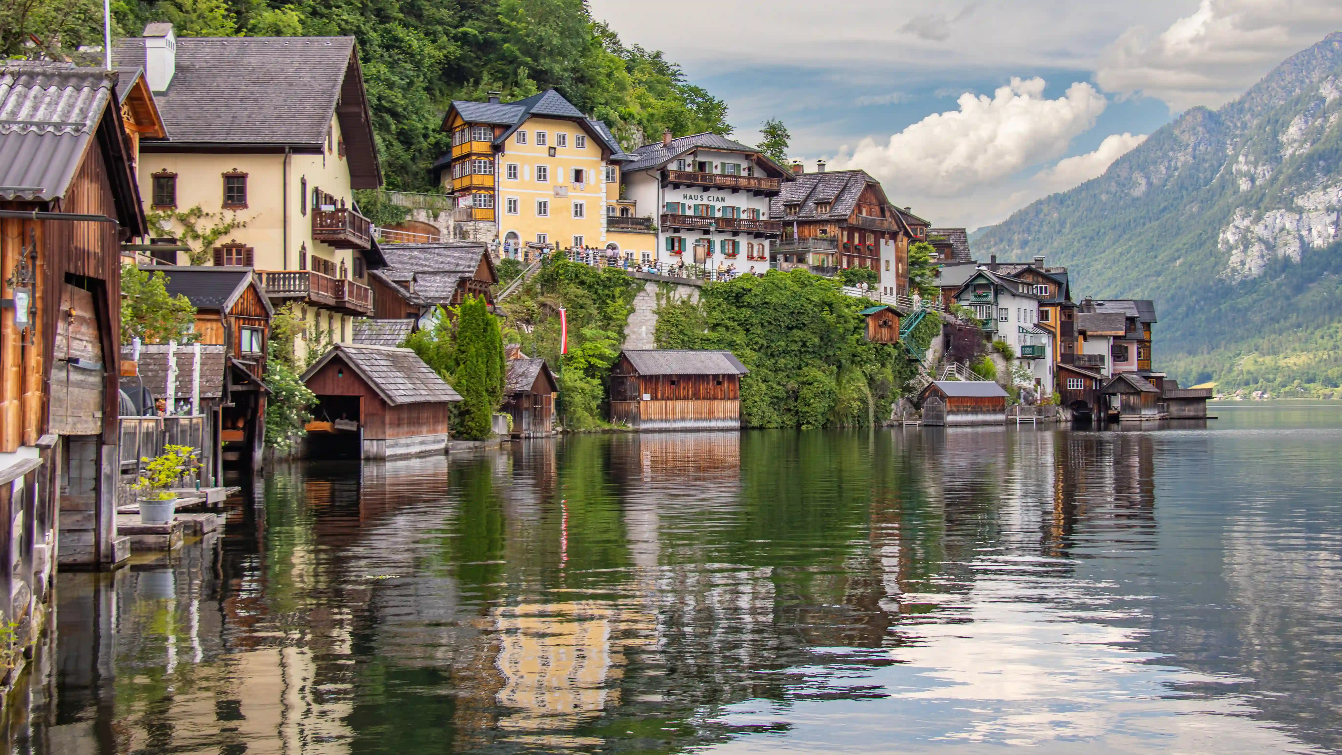 Colorful houses lining the edge of Lake Hallstatt with mountains rising behind the village.
