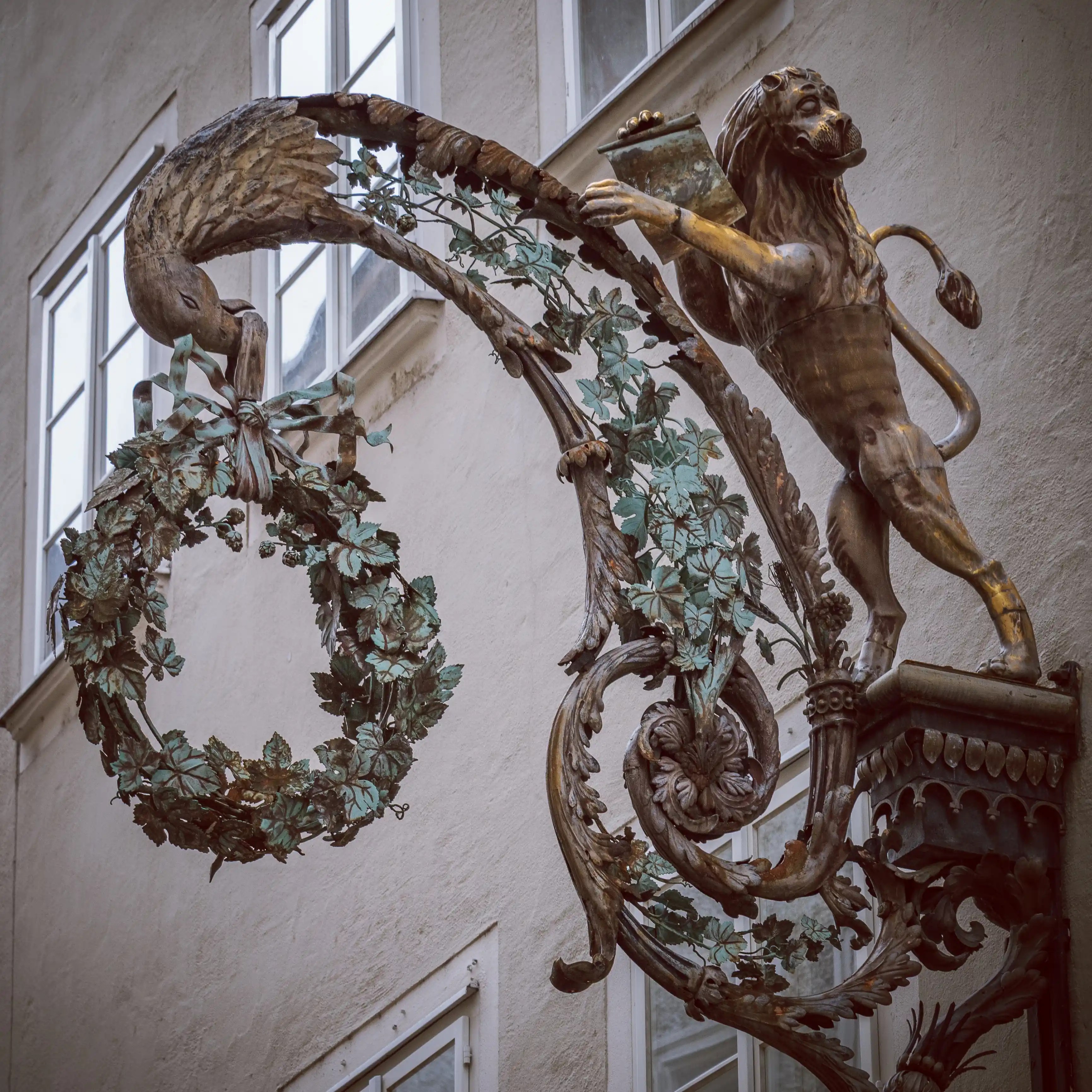 Ornate wrought-iron guild sign featuring a lion and decorative wreath in Salzburg.