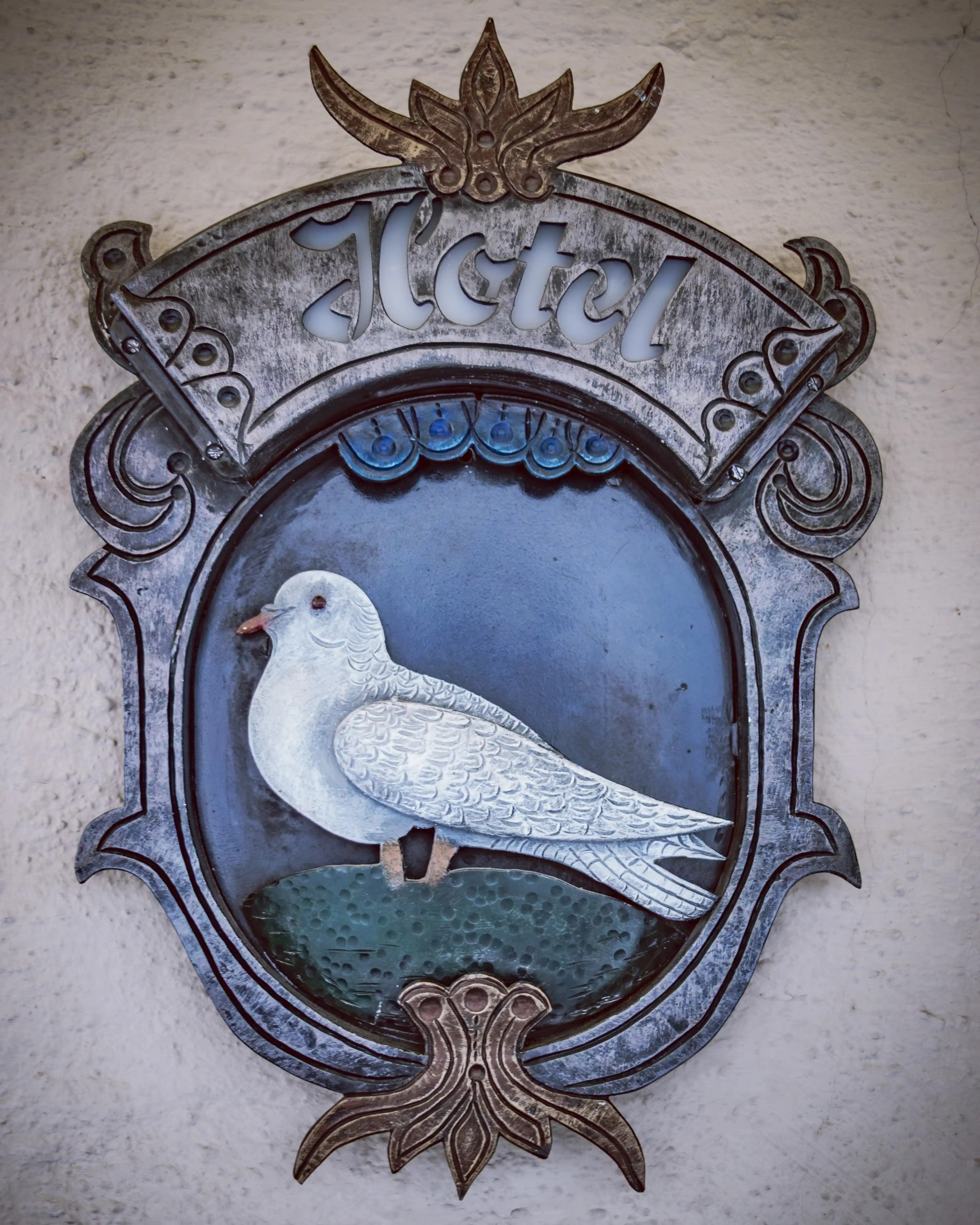 Decorative metal sign with a white dove reading “Hotel” at Hotel Weisse Taube in Salzburg.