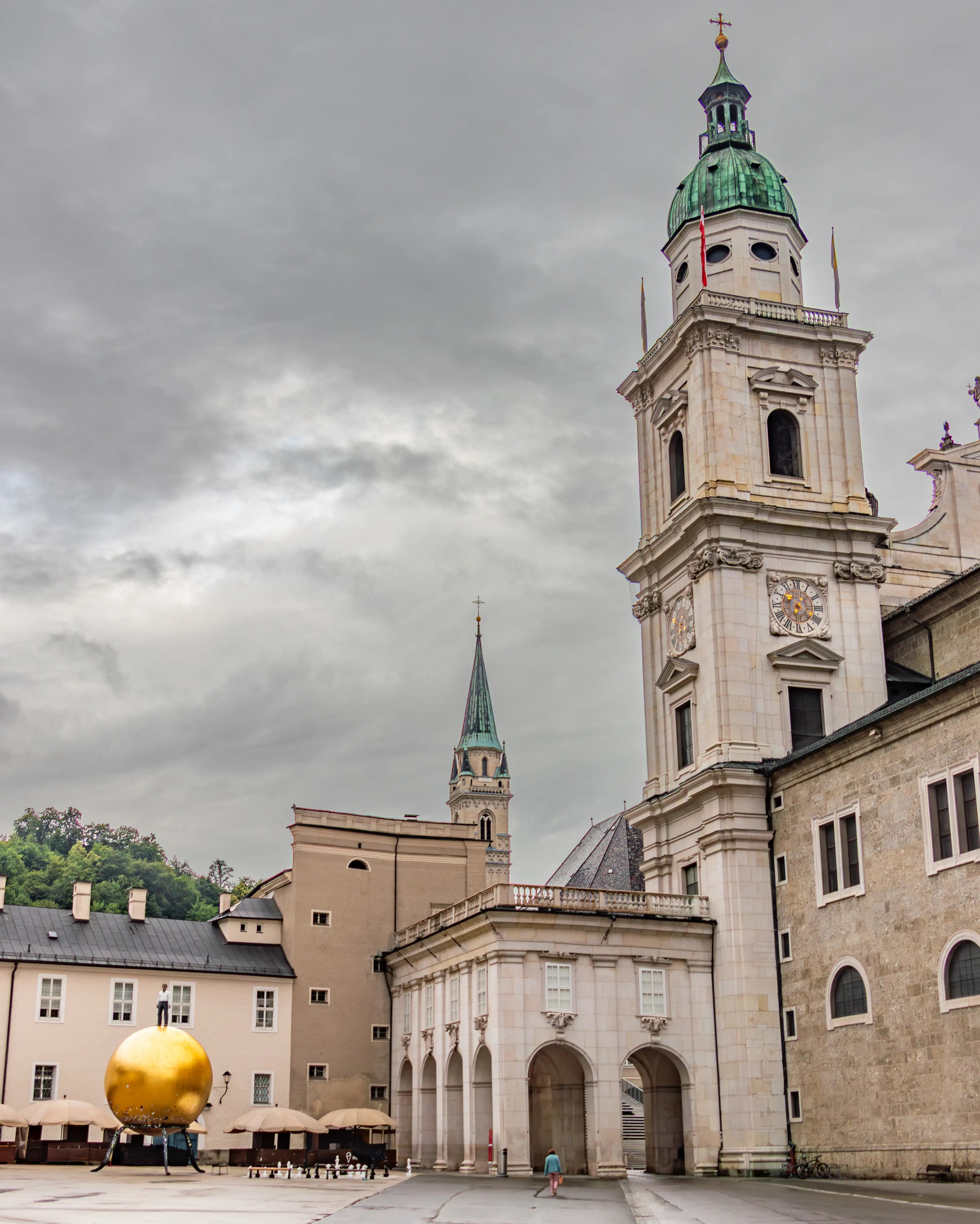 One of Salzburg Cathedral’s towers rises above Kapitelplatz, with the gold "Sphaera" sphere sculpture visible in the square below.