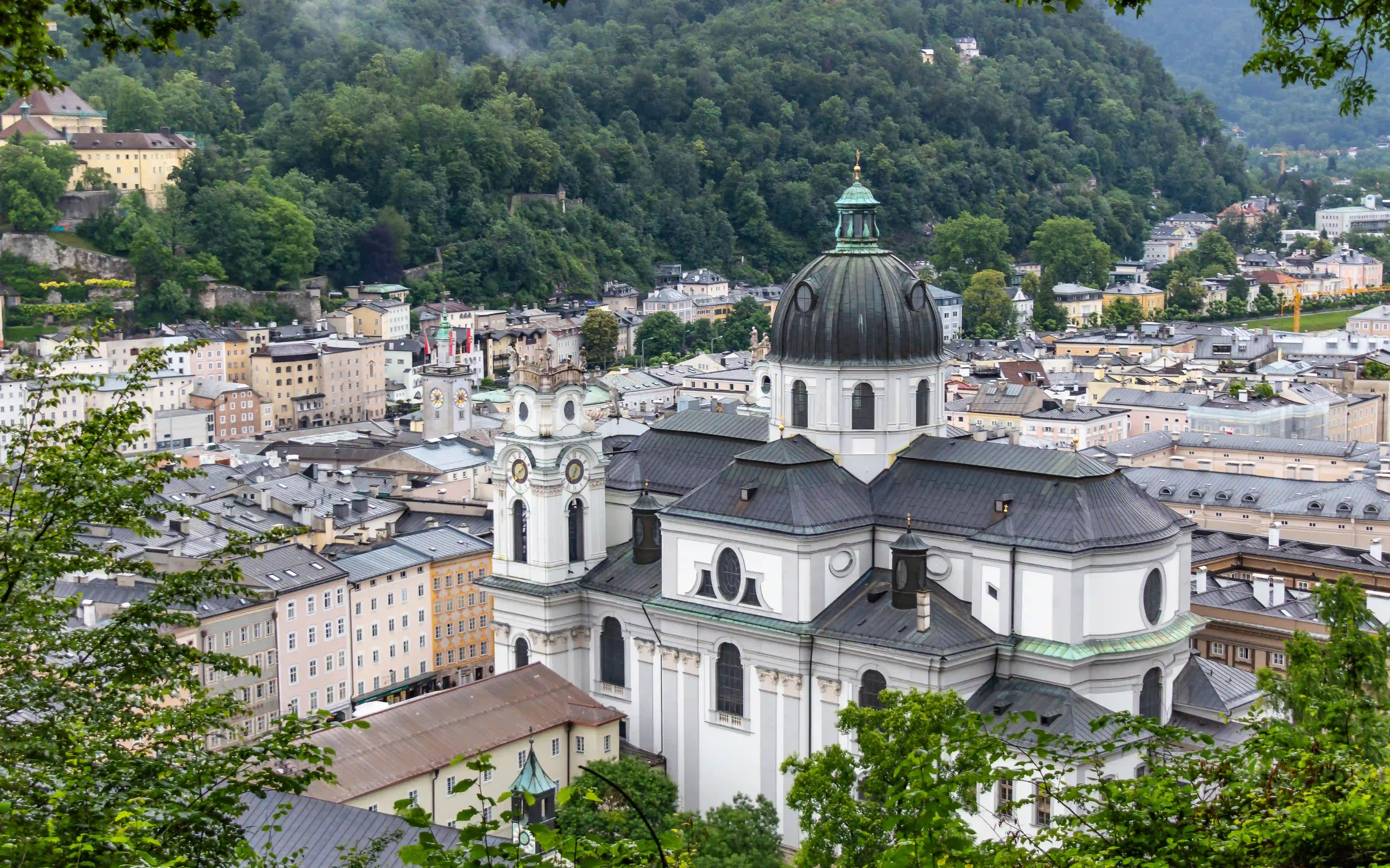 The white domed Collegiate Church seen from above, surrounded by Old Town rooftops and backed by a wooded hillside.