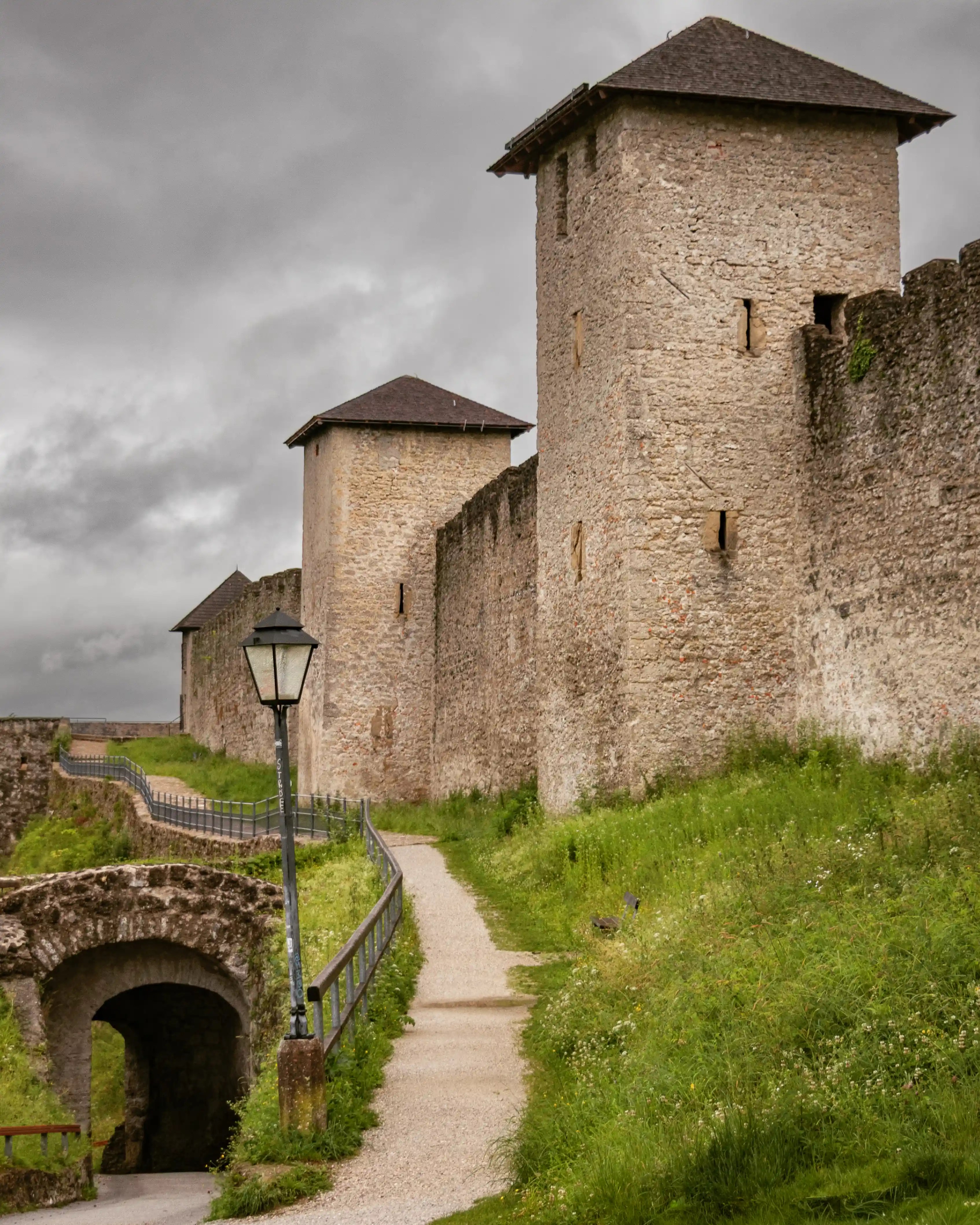 A narrow path running beside thick stone fortification walls with square towers along the Burgerwehr on the Mönchsberg.