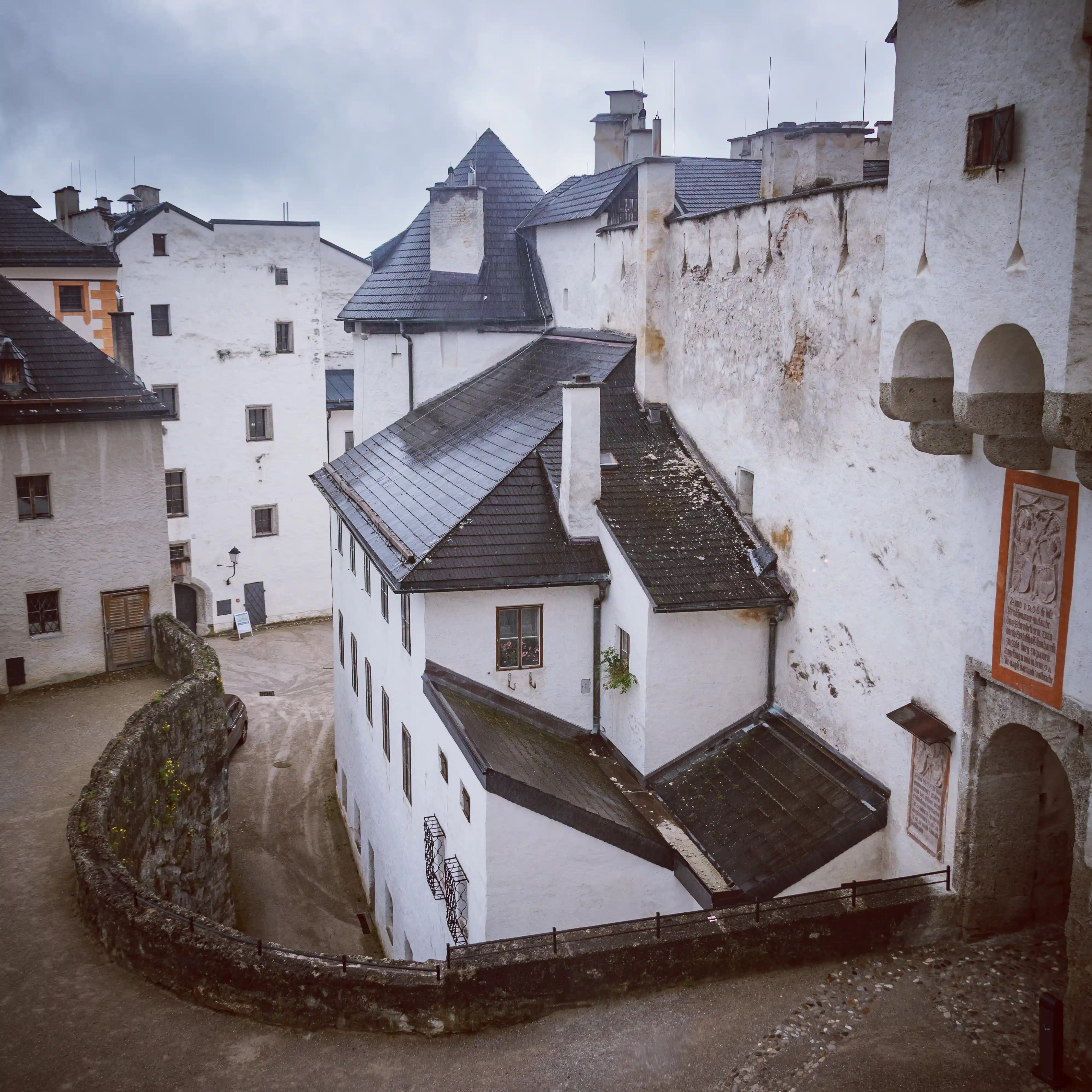 White stone buildings with layered rooftops and chimneys sit tightly within thick fortress walls under an overcast sky.