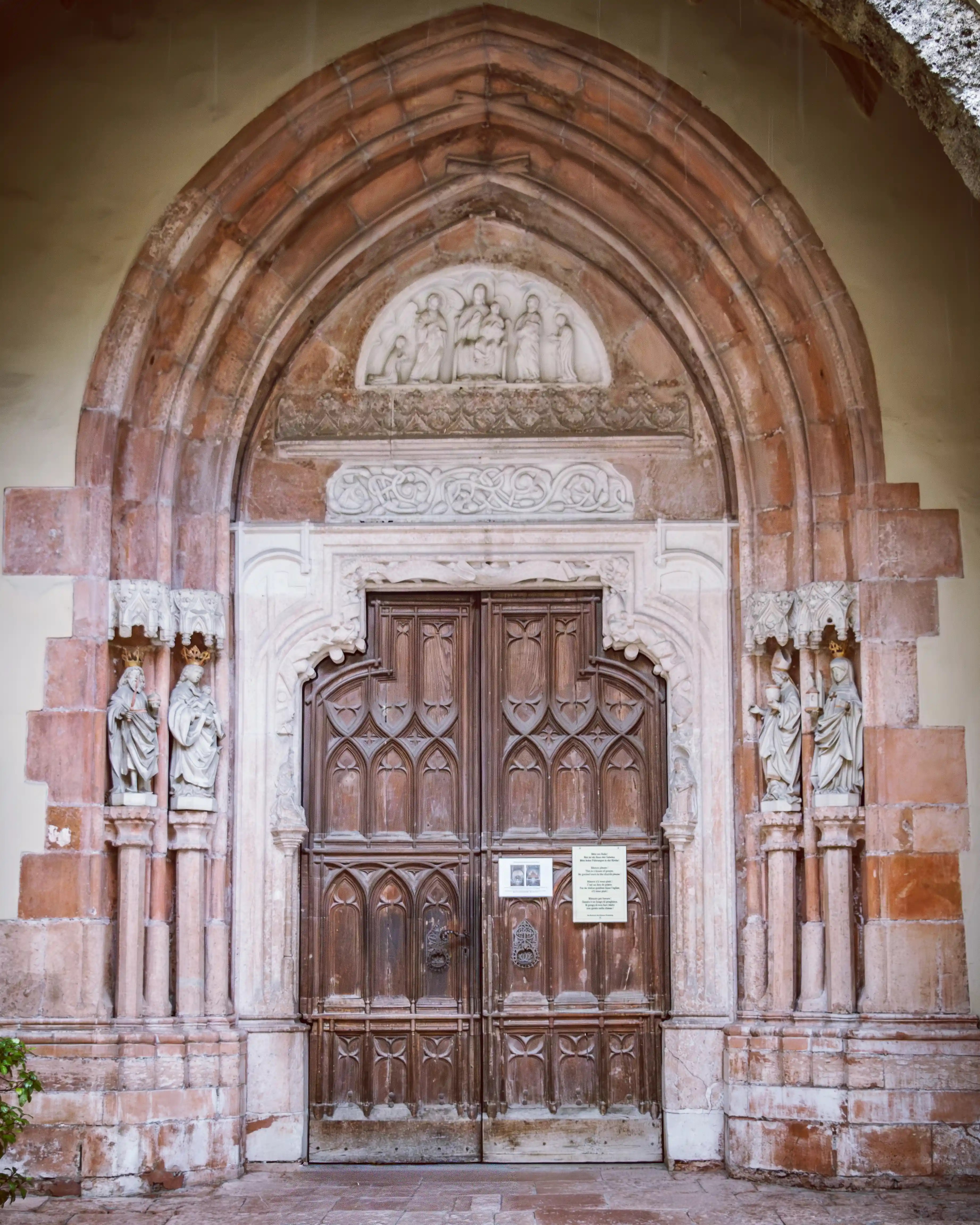 A Romanesque stone doorway with carved figures and a wooden double door at the entrance to Nonnberg Abbey in Salzburg.