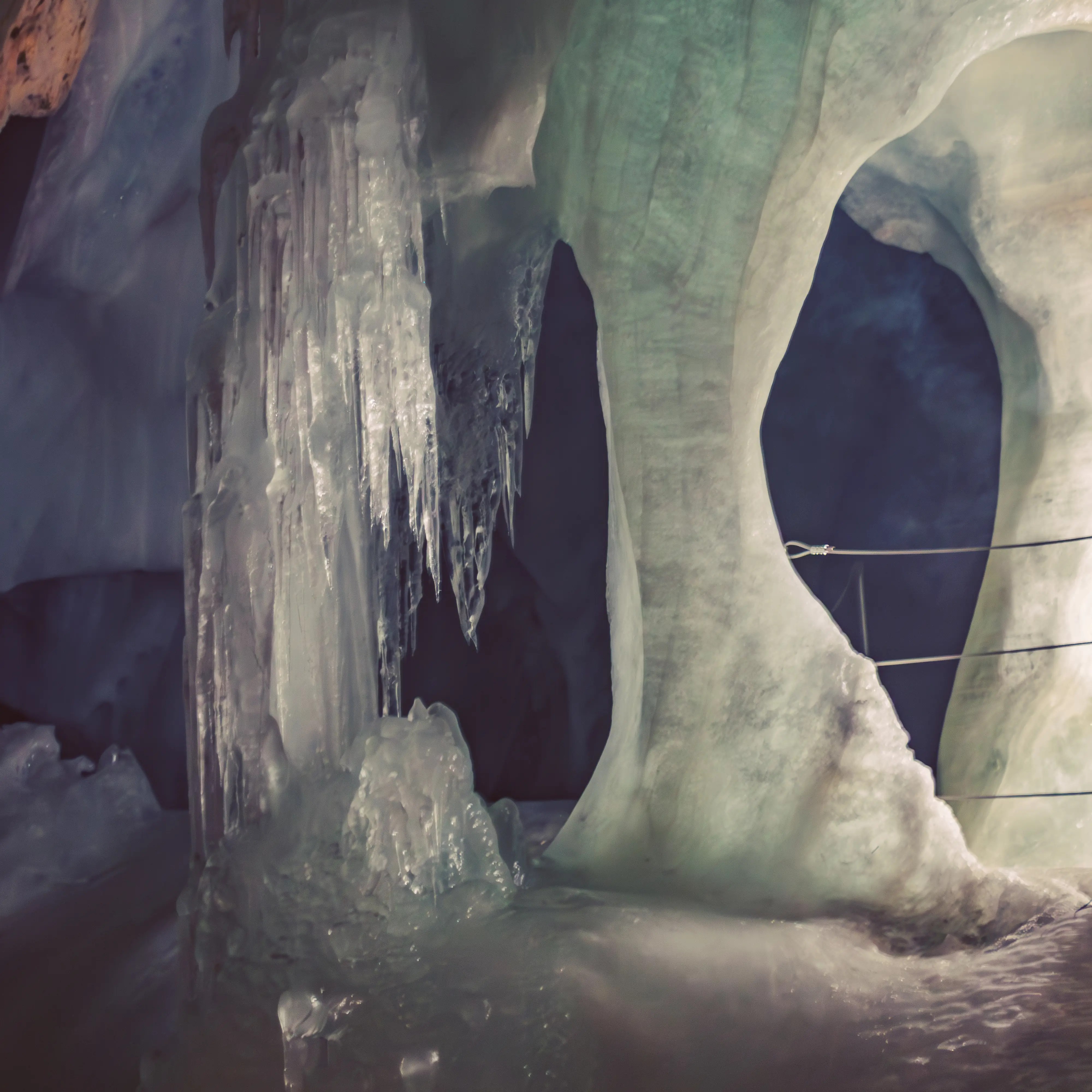 Thick ice columns and frozen drips form natural arches inside Eisriesenwelt, glowing softly under cave lighting.