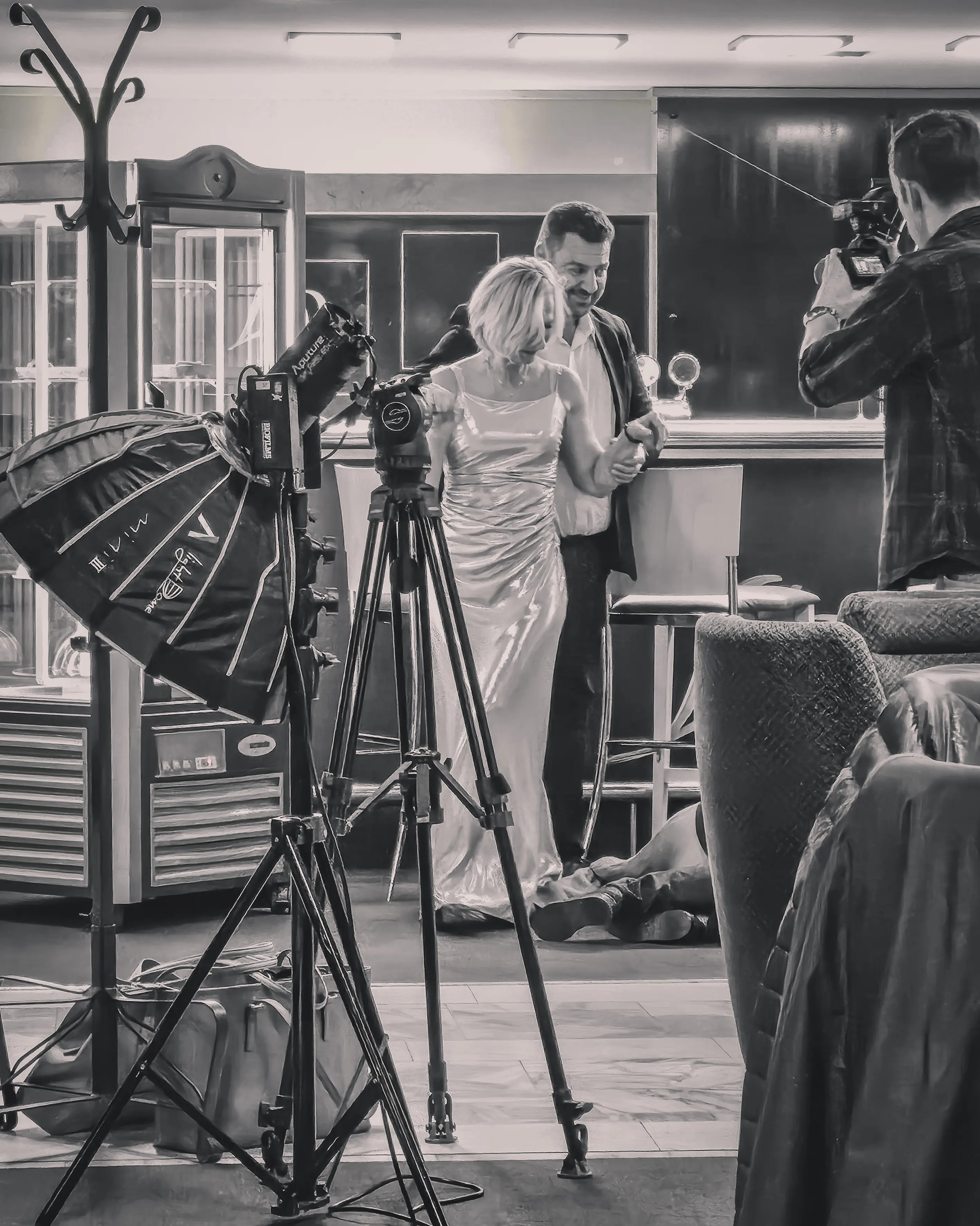 A film crew sets up cameras and lights inside a bar at Hotel Thermal in Karlovy Vary while actors prepare for a scene.