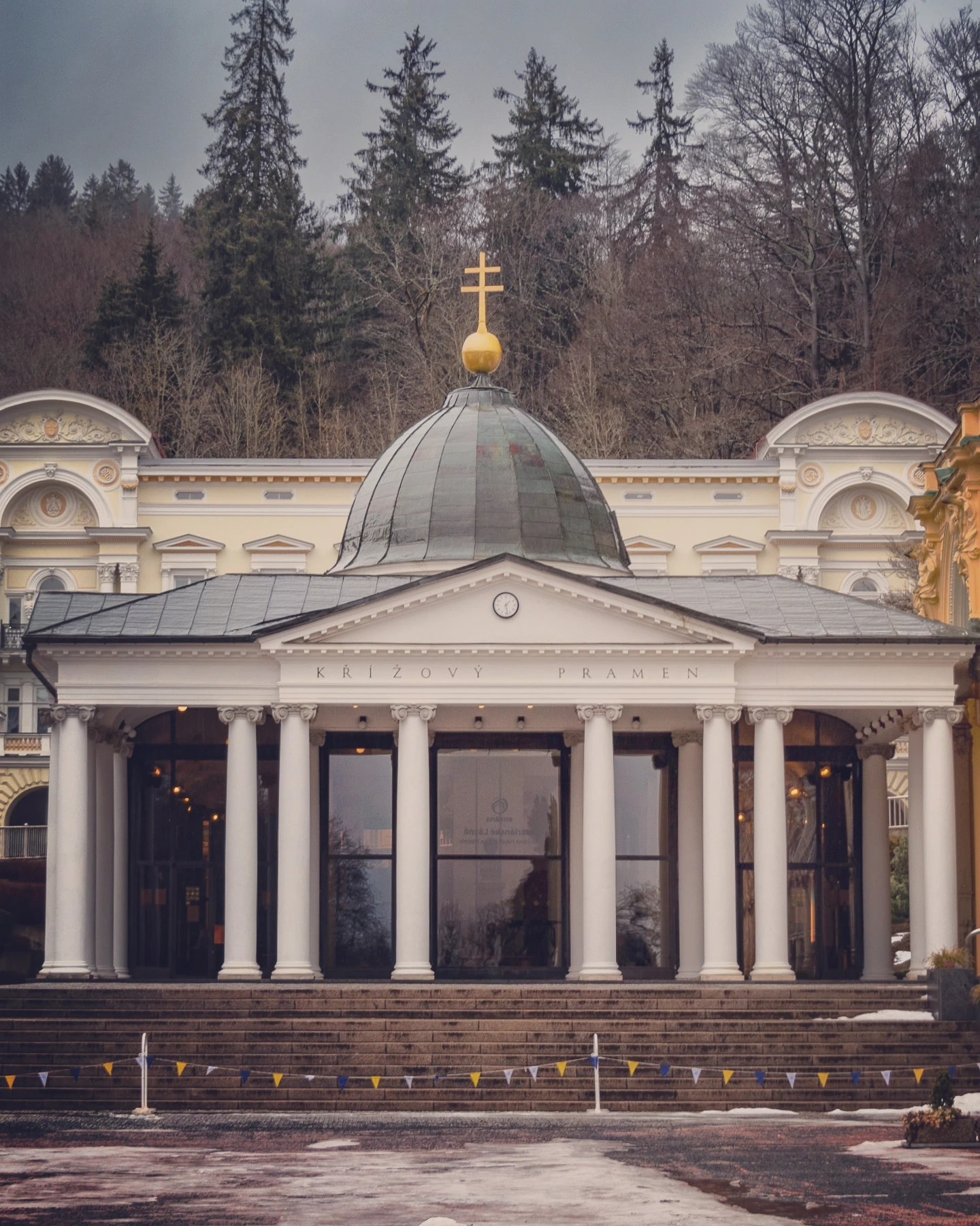 The Main Colonnade with white columns, a central dome topped by a golden cross, and steps leading up from the square in Mariánské Lázně.