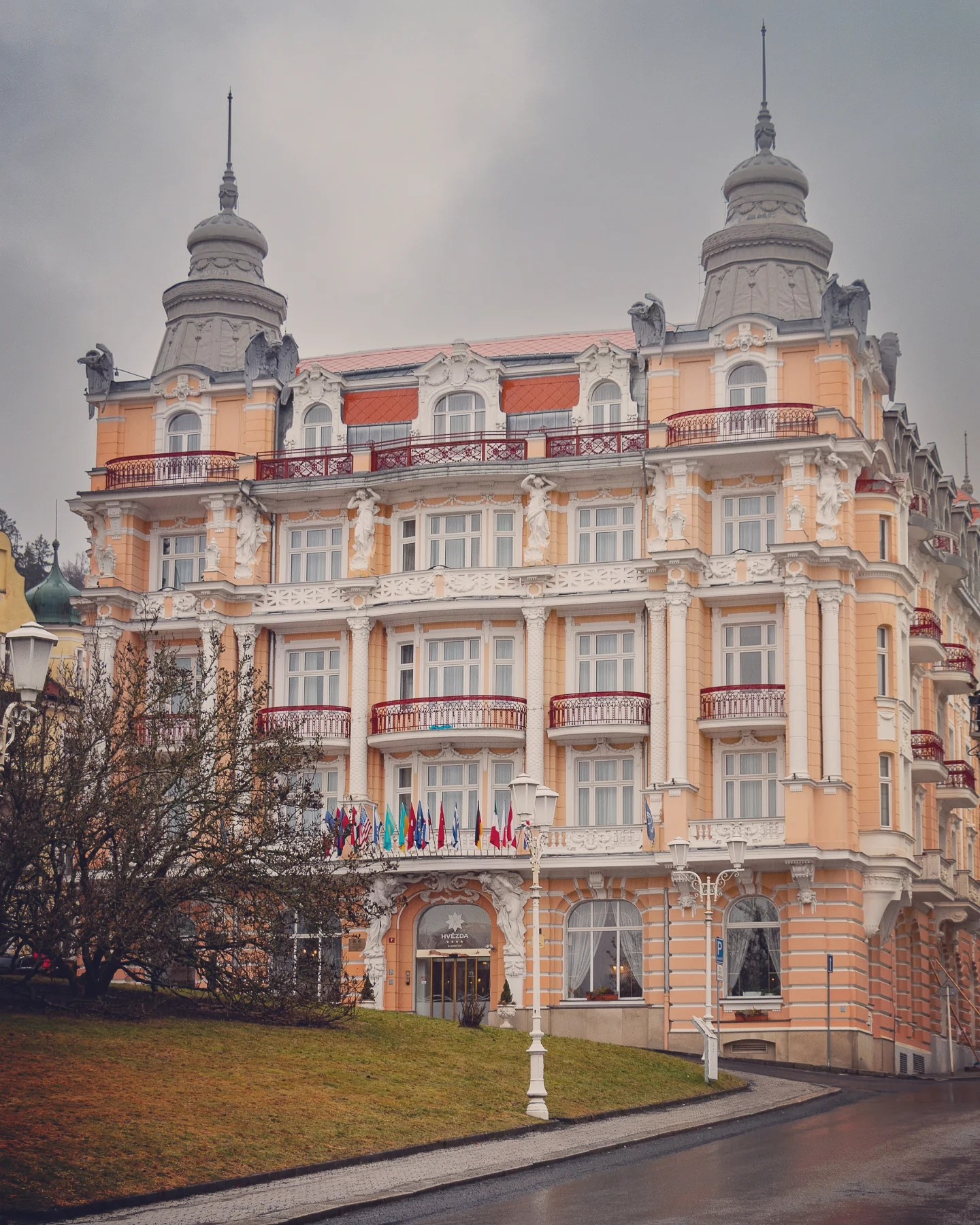 An ornate pastel-colored spa hotel with balconies and decorative towers in Mariánské Lázně.