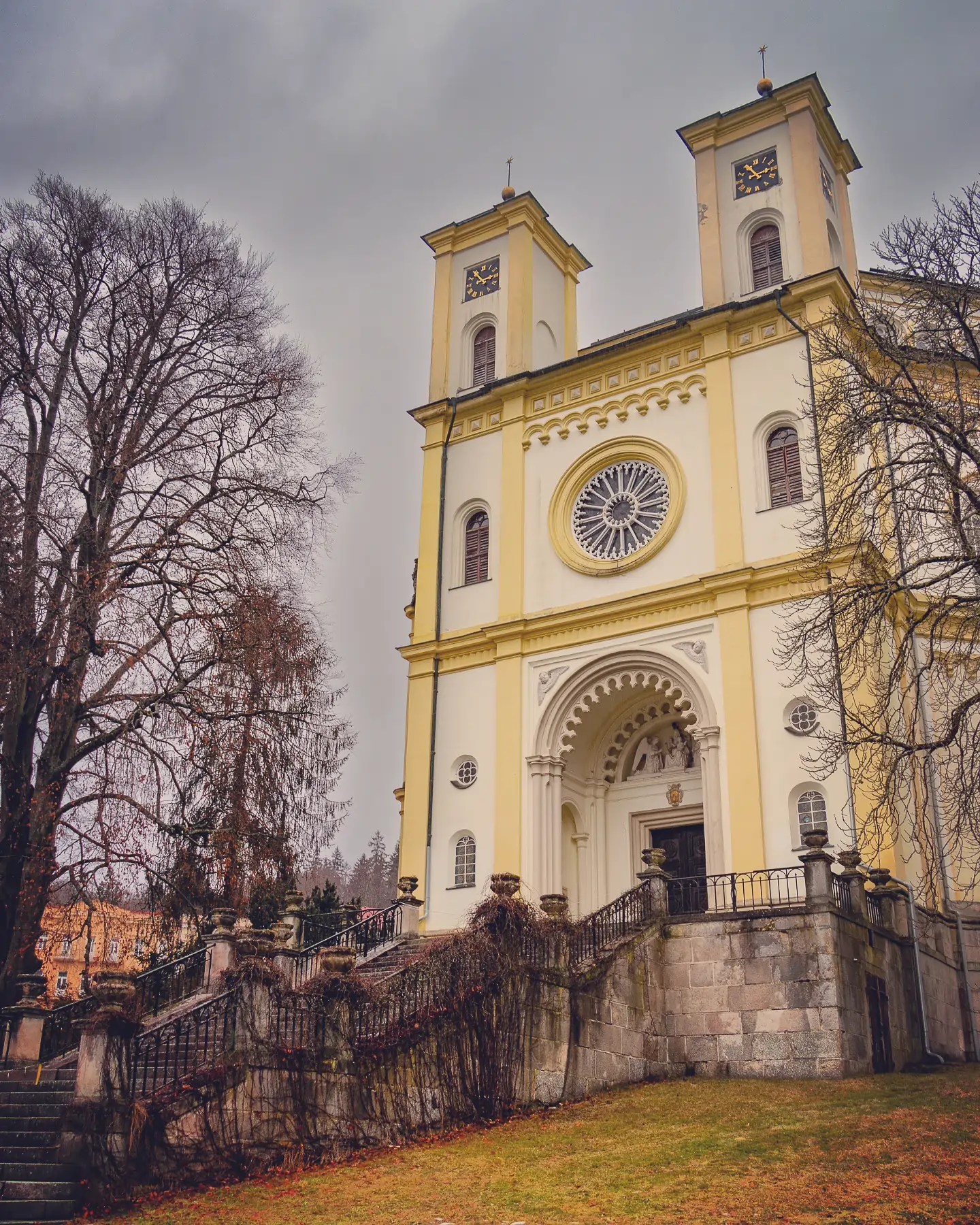 The yellow façade of the Church of the Assumption of the Virgin Mary with twin towers in Mariánské Lázně.