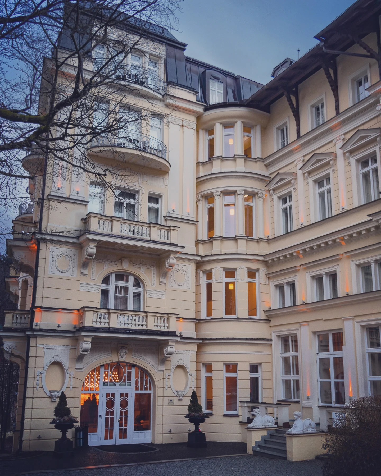 The ornate yellow-colored façade of Falkensteiner Spa Resort with balconies and decorative moldings in Mariánské Lázně.