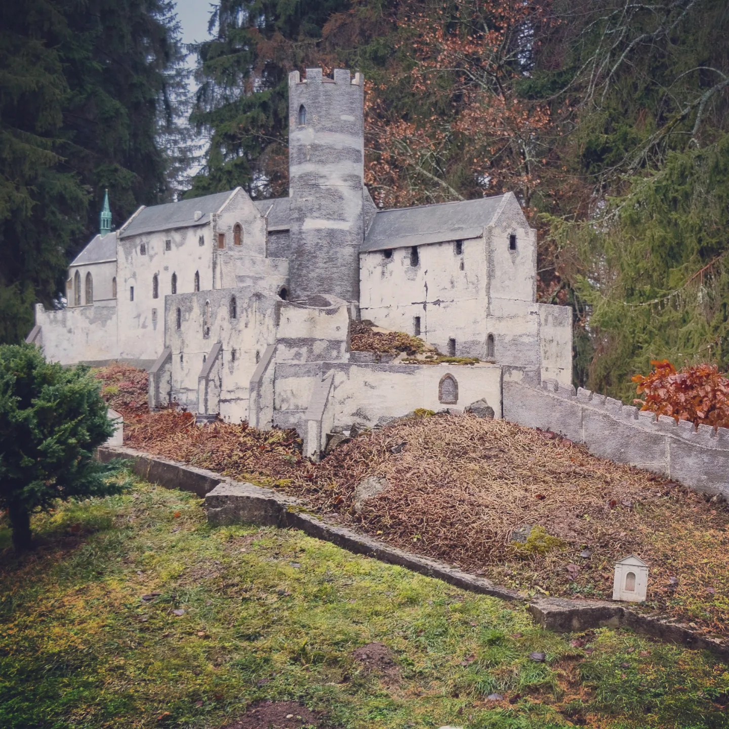 A gray stone miniature monastery or fortress with a central tower displayed in Park Boheminium.