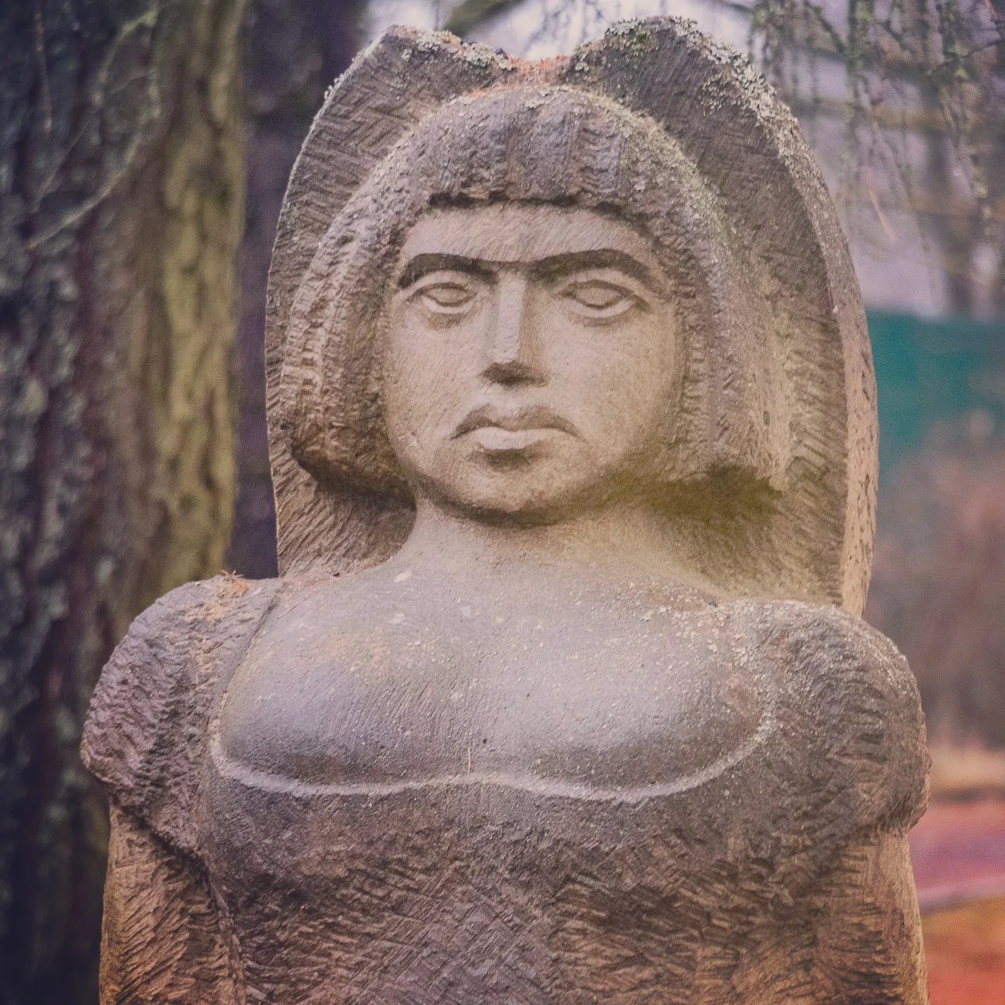 A close-up of a carved stone sculpture of a woman with stylized hair and a solemn expression.