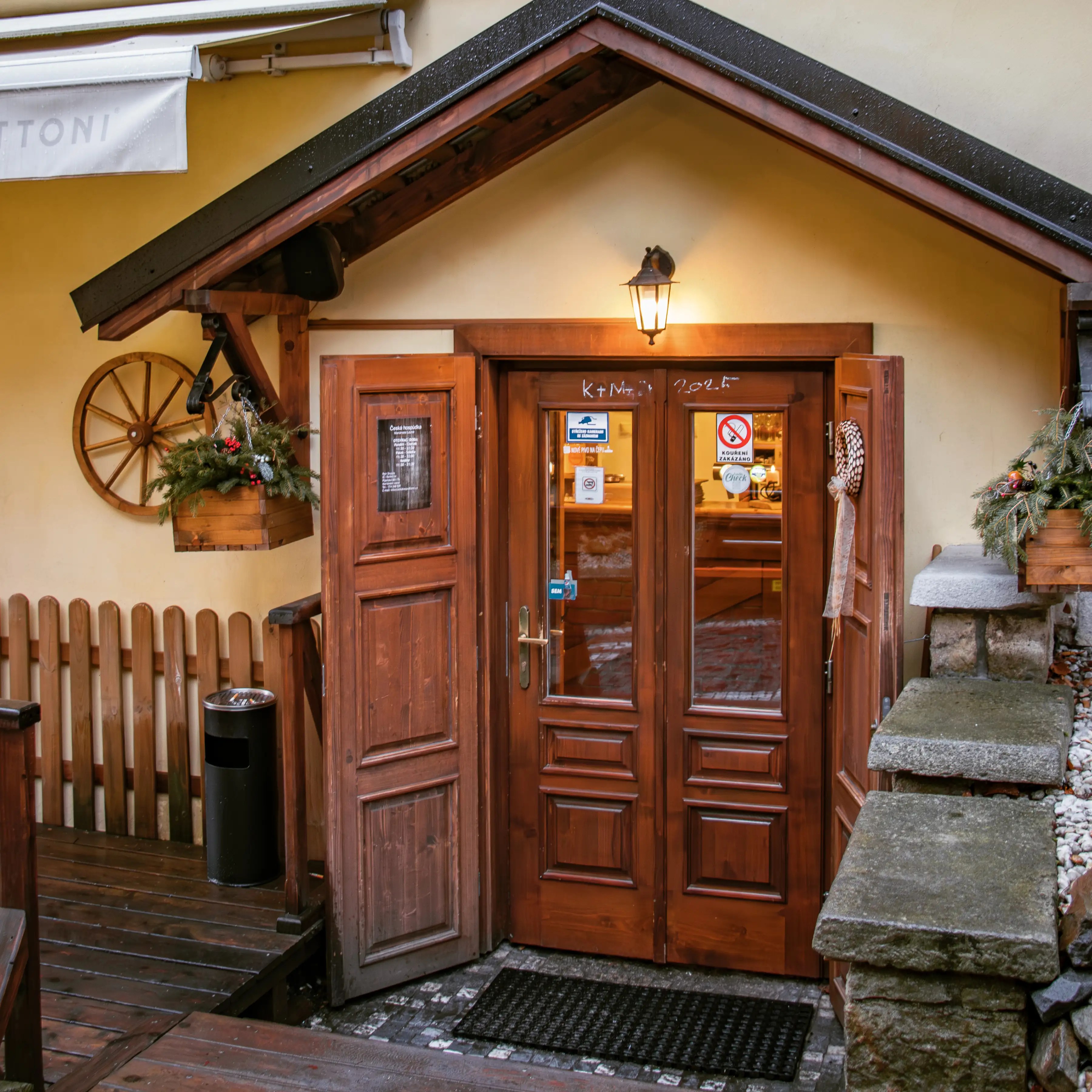 A wooden double-door entrance with rustic decor and a lantern above the doorway at Česká Hospůdka in Mariánské Lázně.