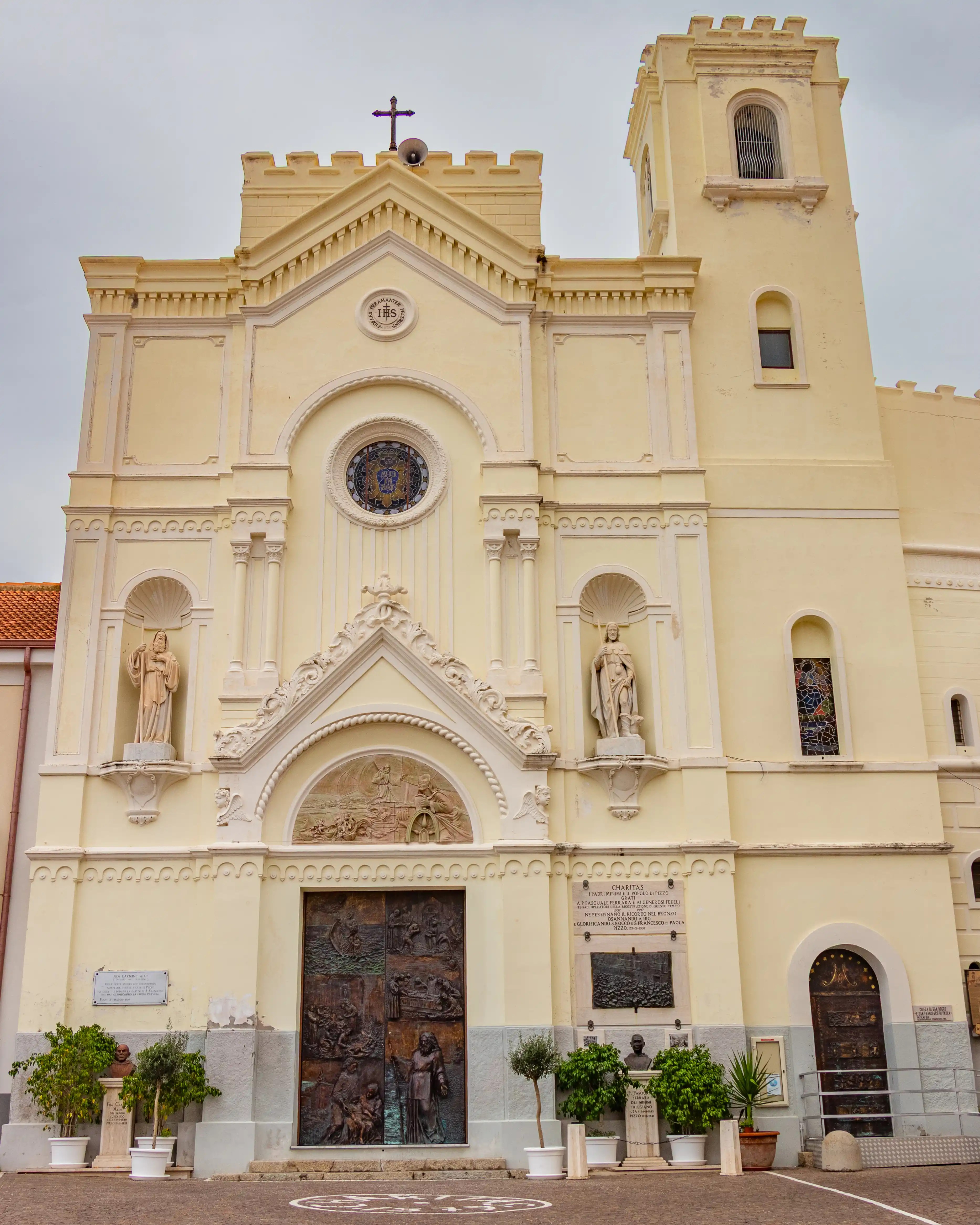 A large church facade with statues, a central round window, and a bell tower on one side.