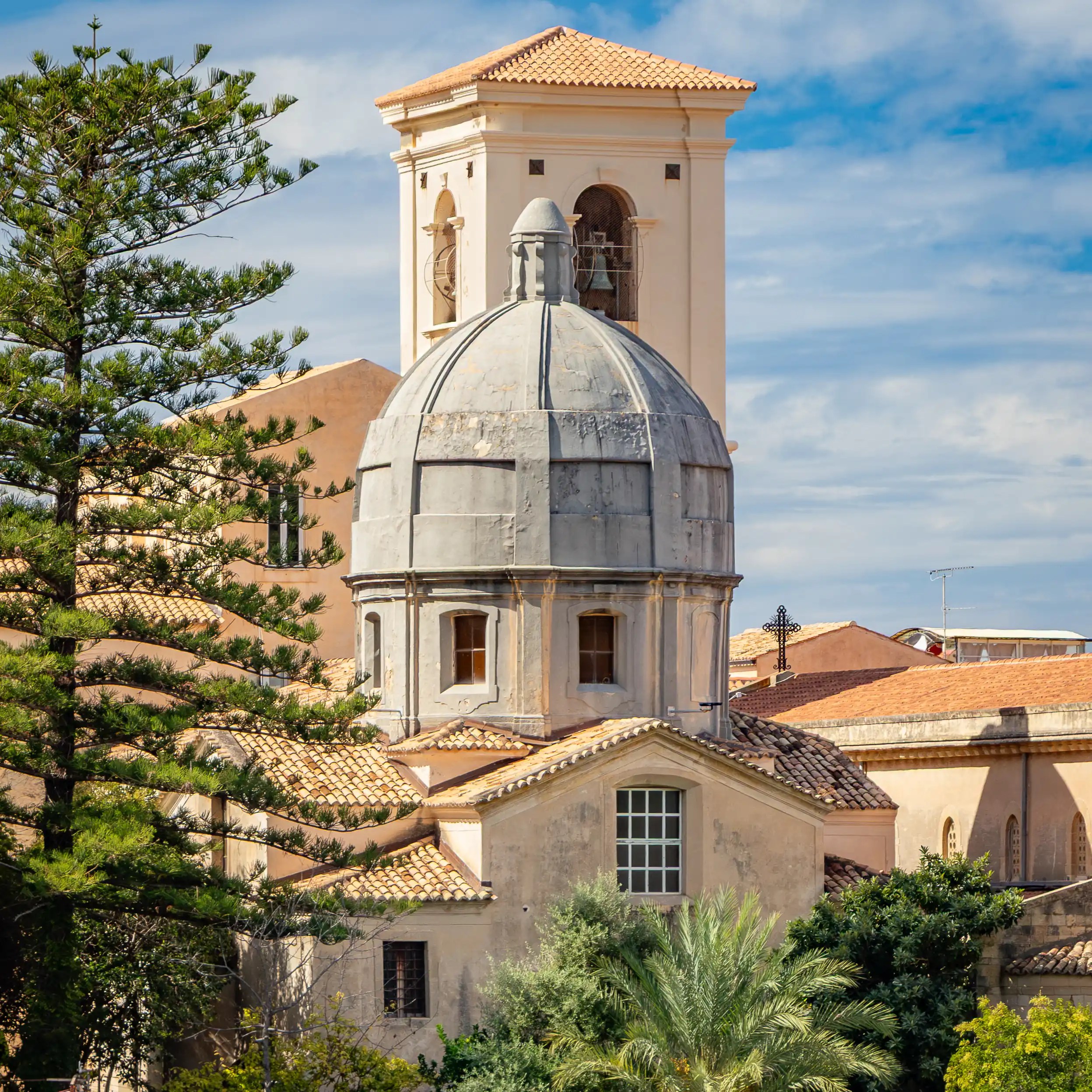 Domed structure and bell tower within the cathedral complex in Tropea, surrounded by historic buildings.