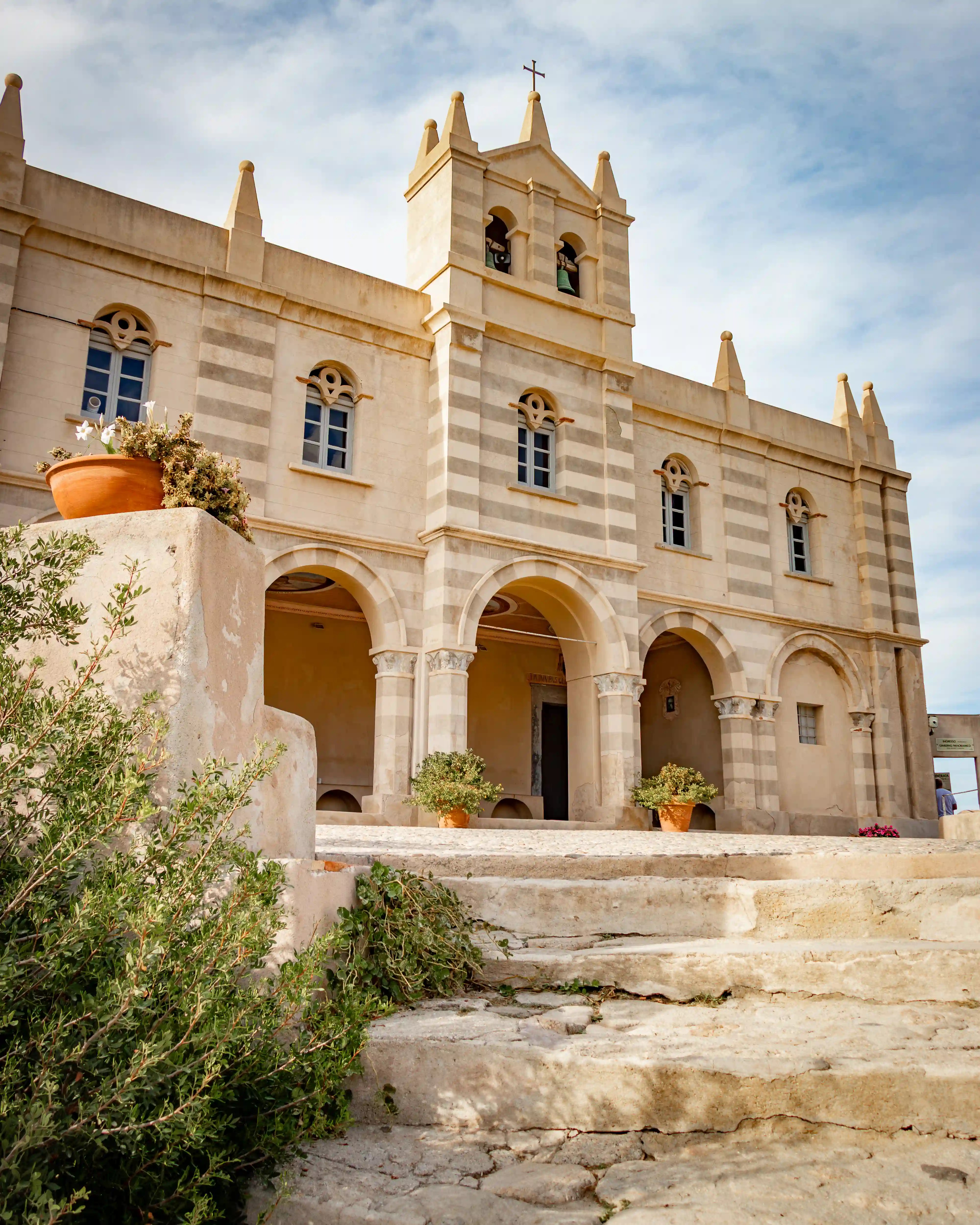 Close view of a light-colored church facade with arches, columns, and small windows.